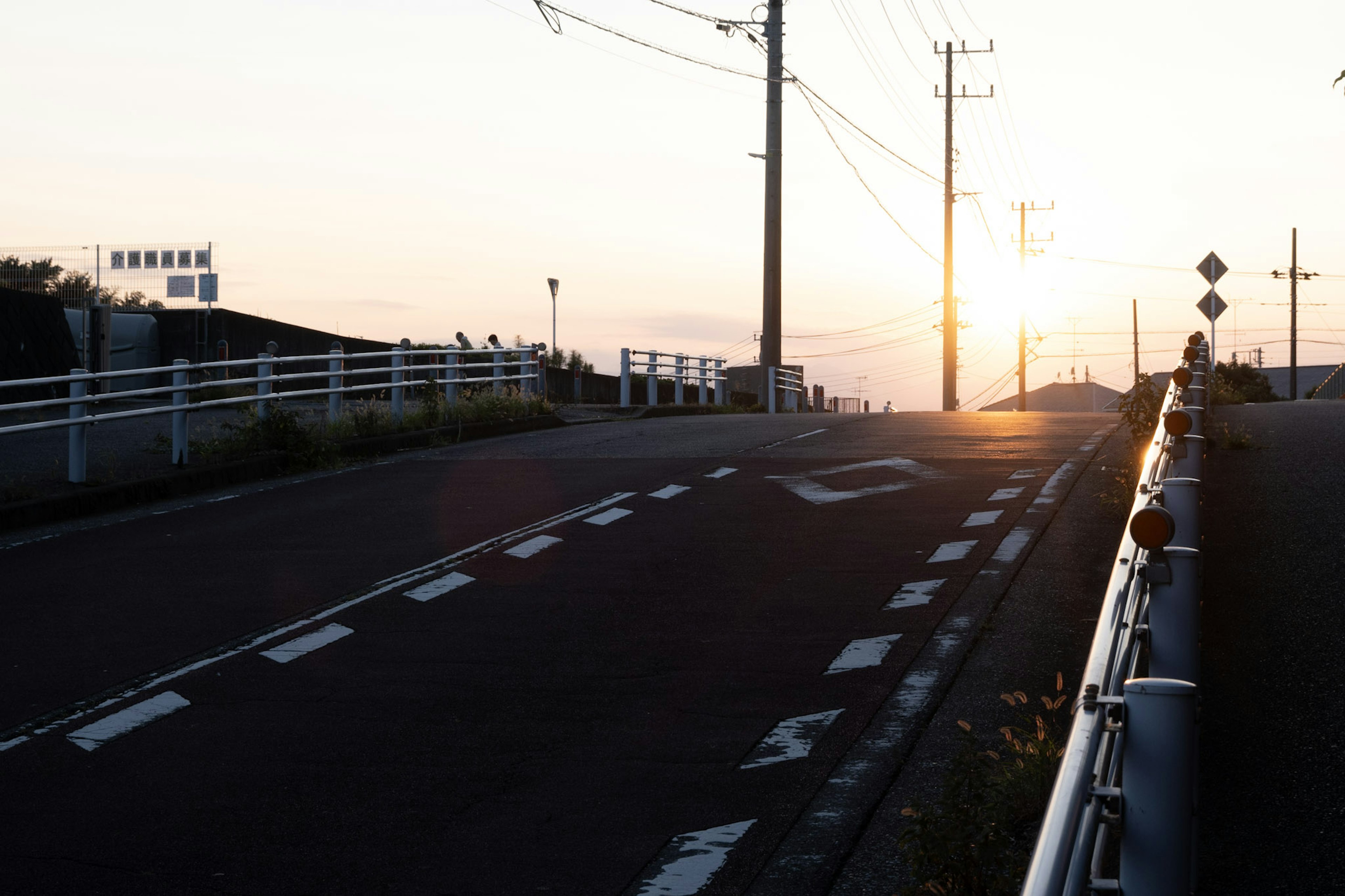 Sunset view of a road with utility poles