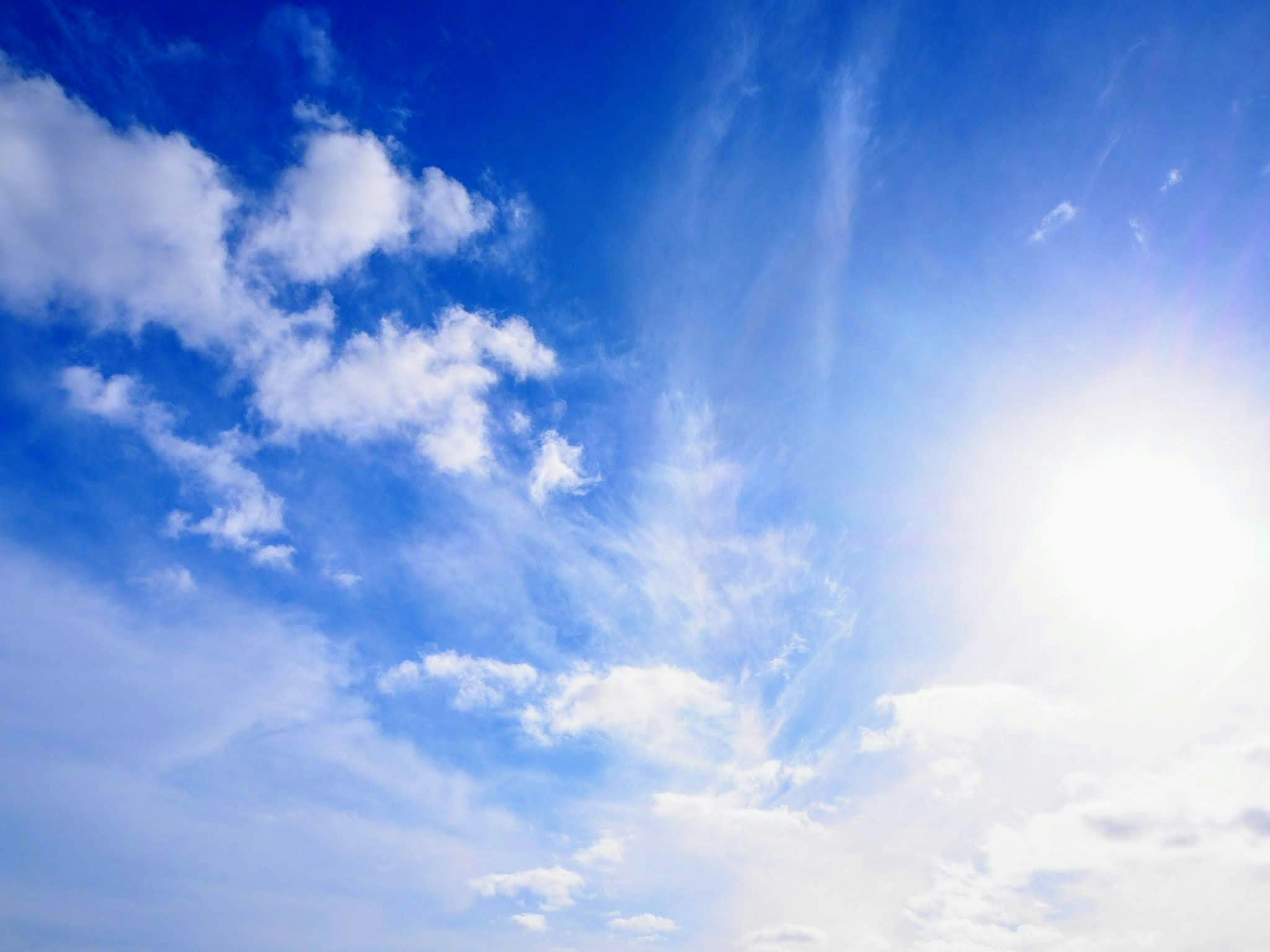 Bright blue sky with fluffy white clouds and sunlight shining