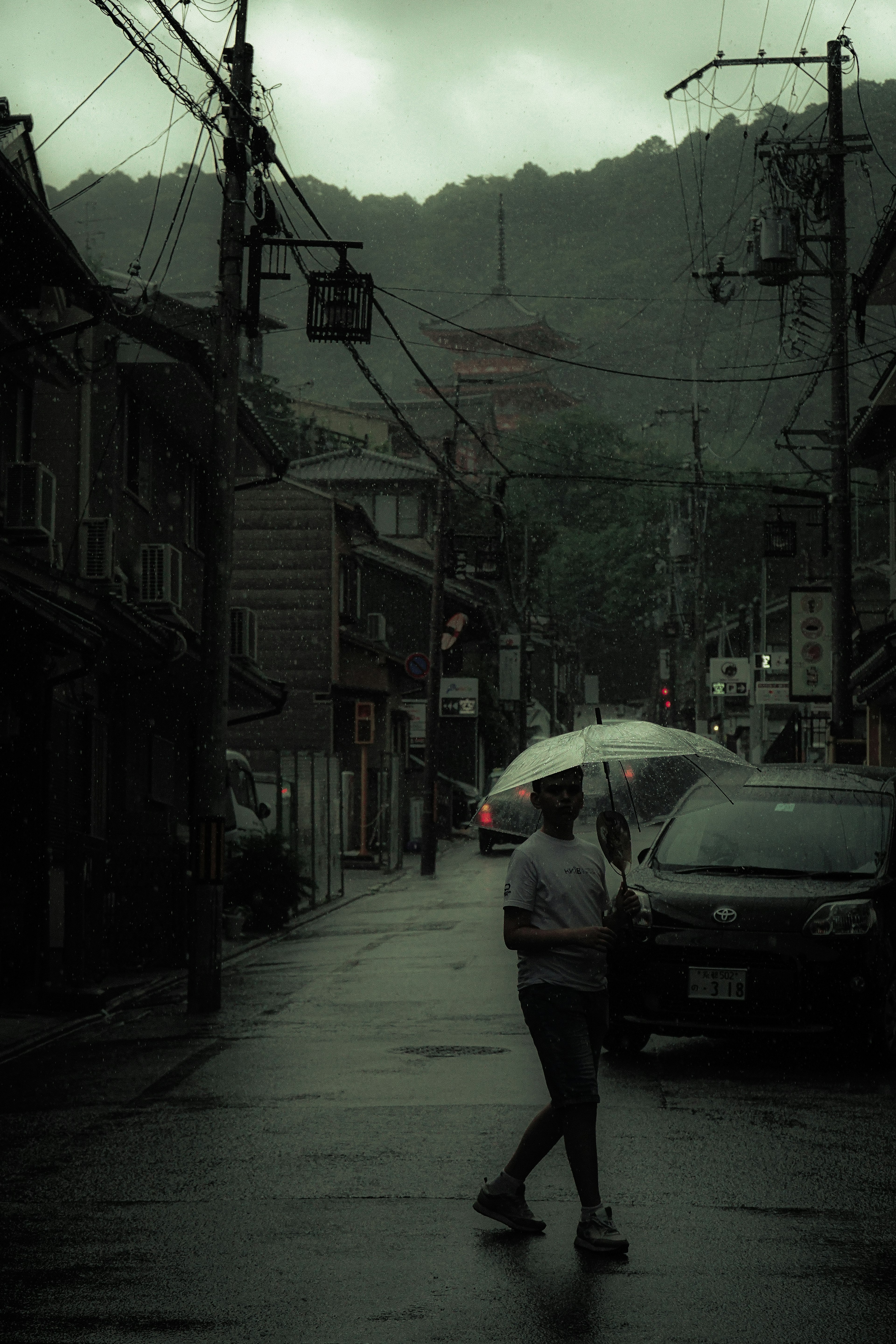 Persona caminando con un paraguas bajo la lluvia y escena de calle oscura