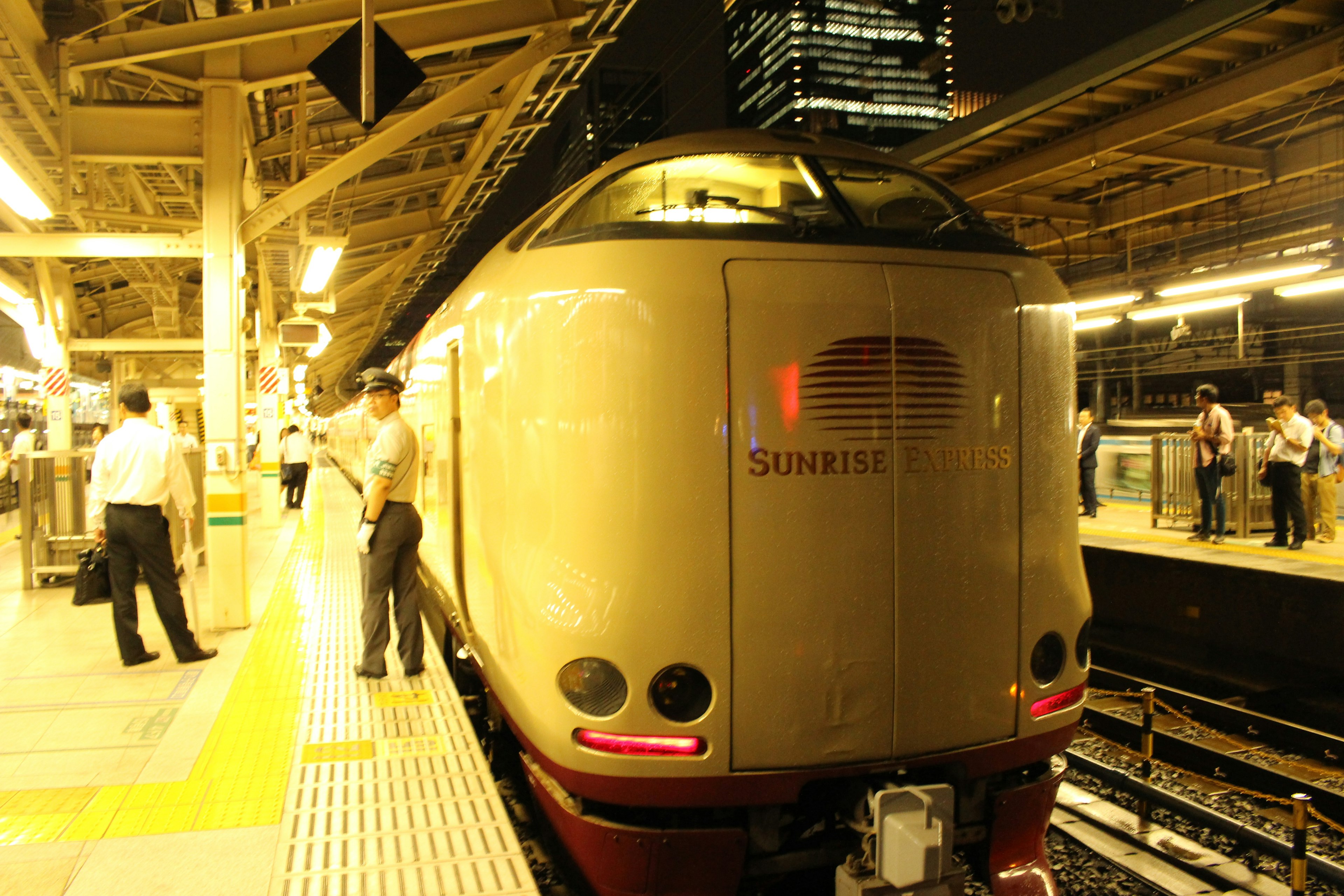 夜の駅で待機中の新幹線の側面と乗客