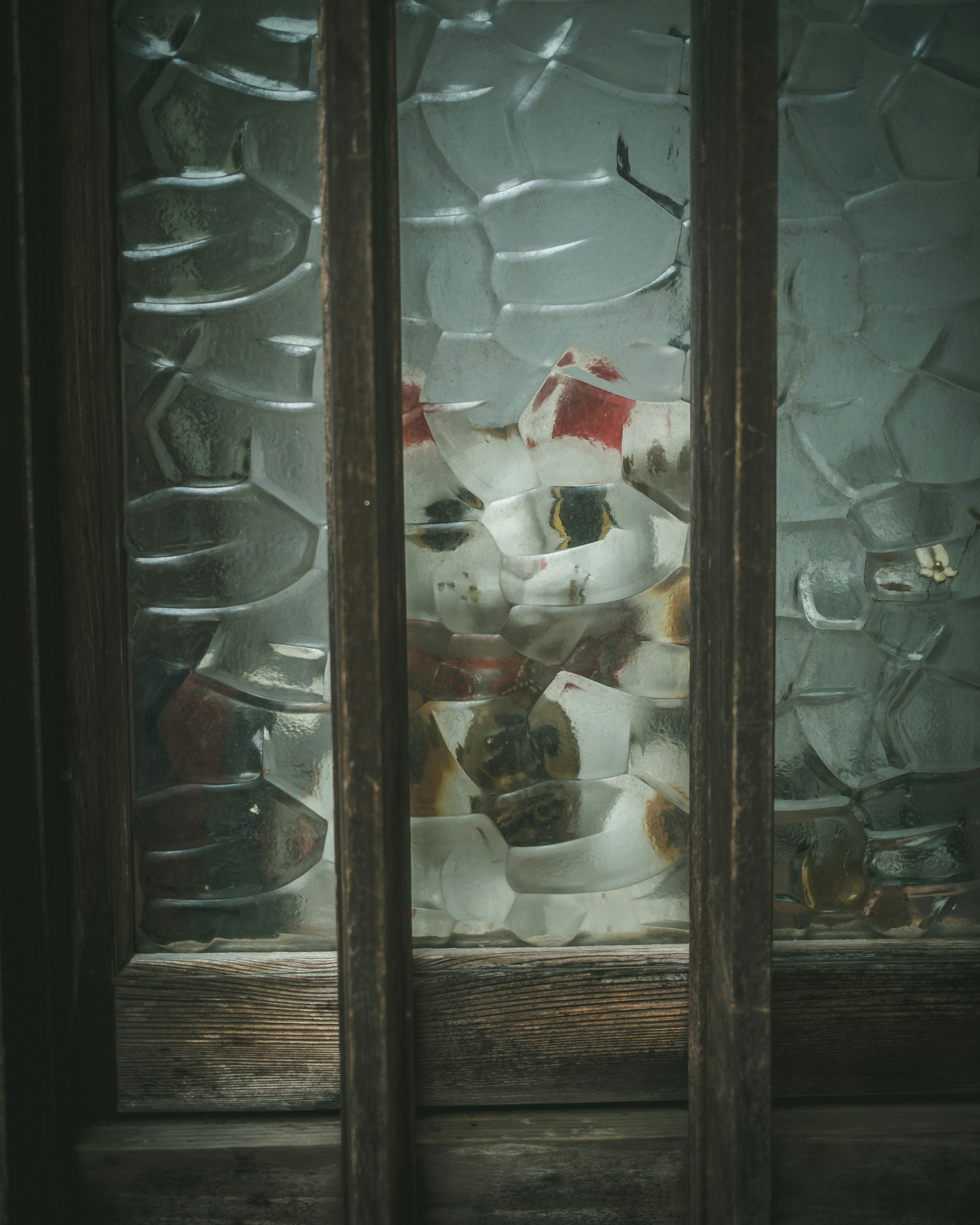 A cluster of white ceramic objects viewed through broken glass