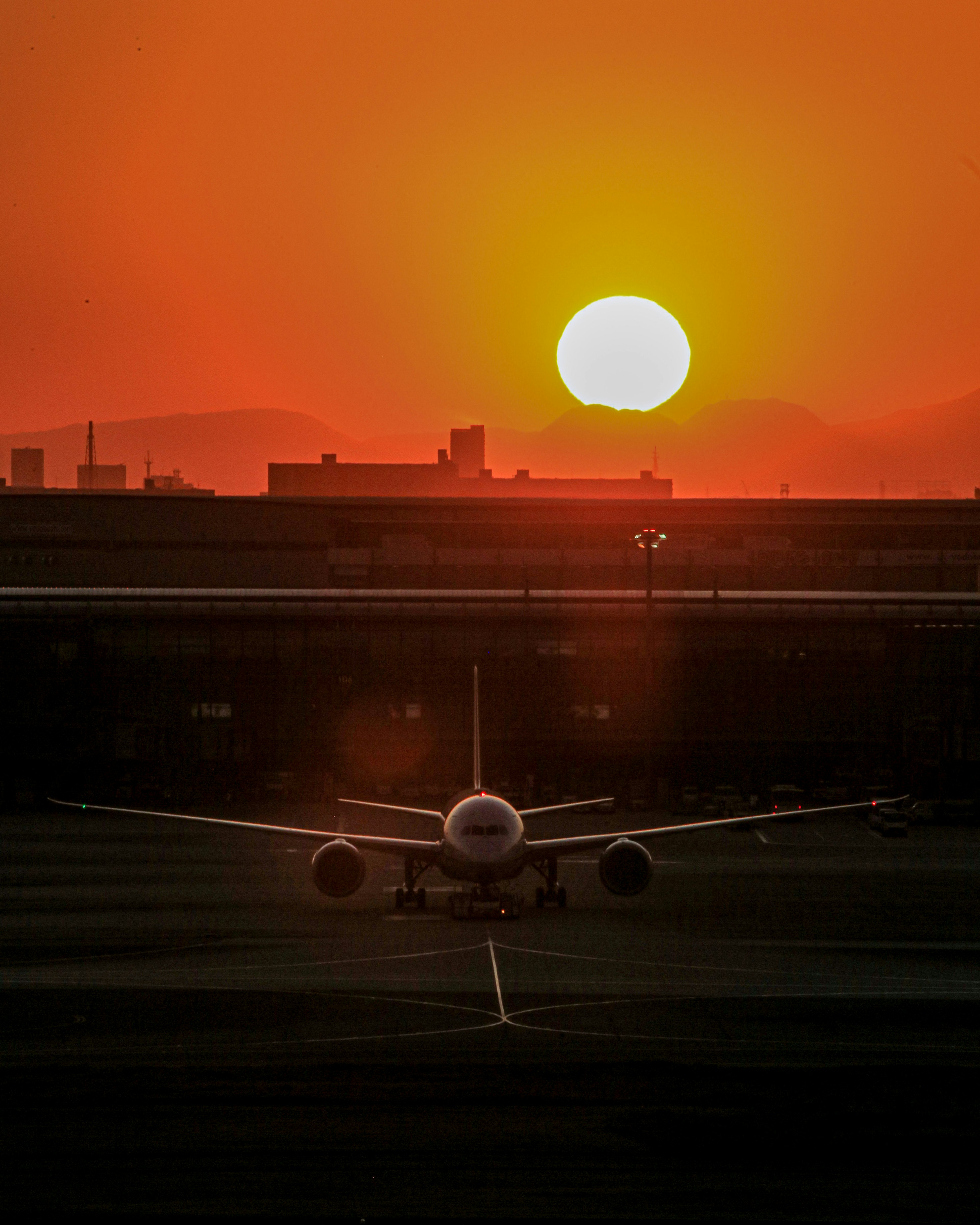 夕日を背景にした滑走路上の航空機