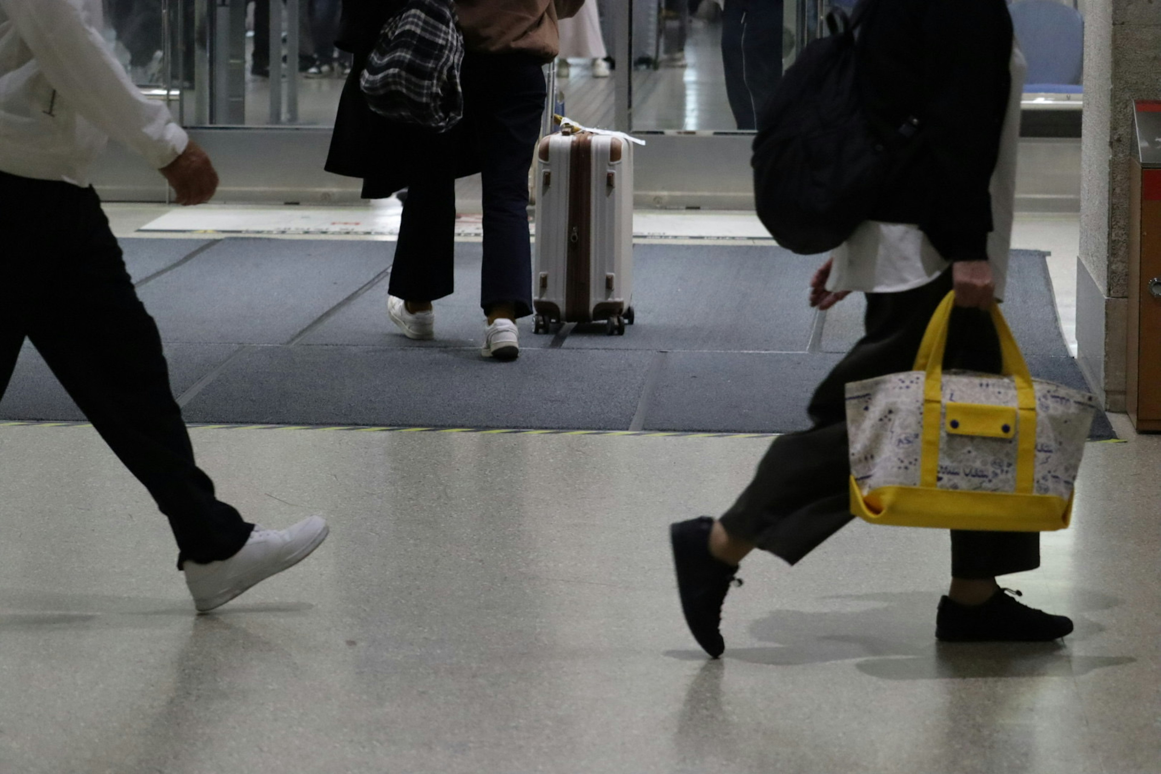 Menschen gehen in einer Bahnszene Person mit einer gelben Tasche