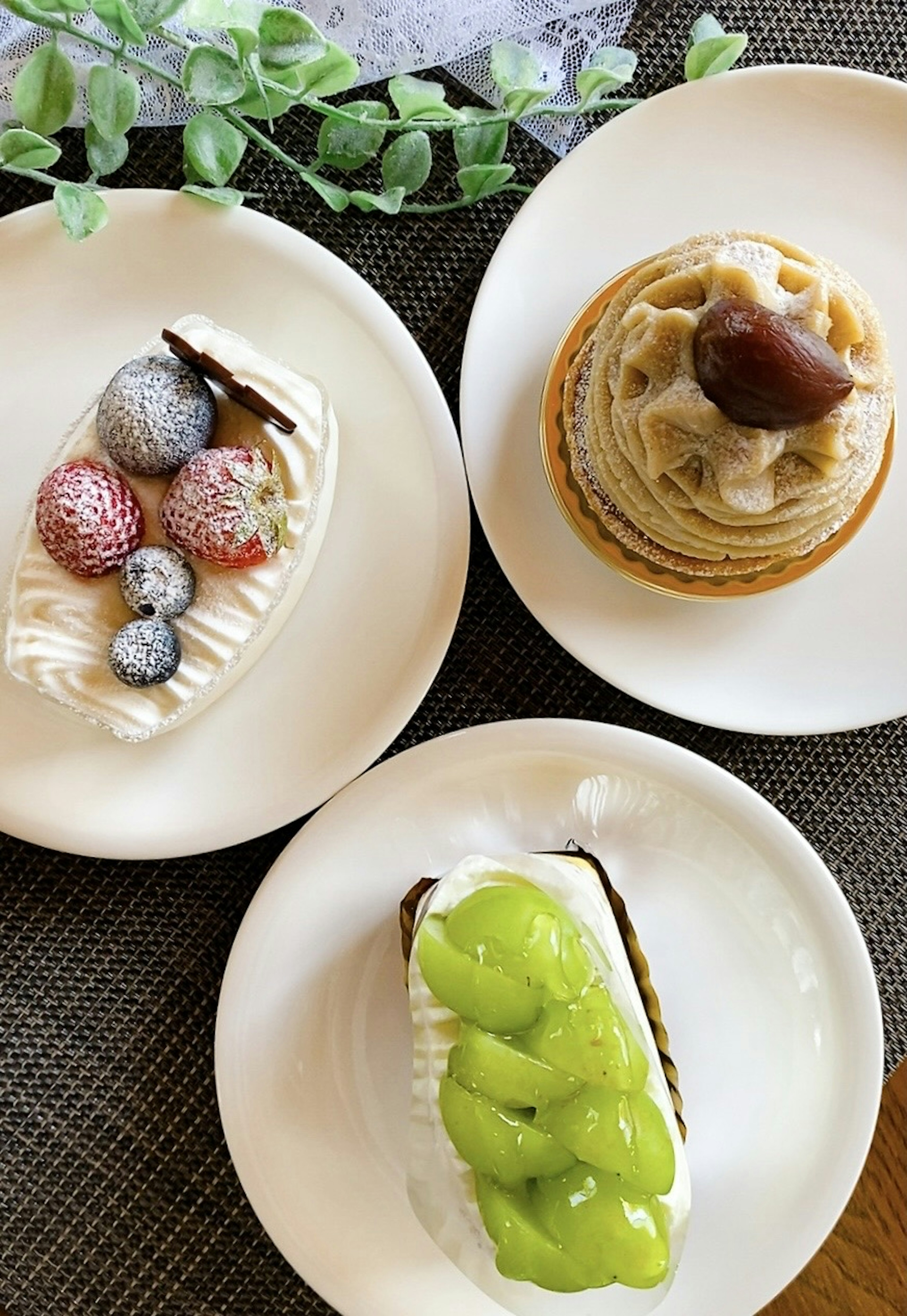 Three distinct desserts displayed on white plates featuring a fruit-topped cake and a chestnut cream dessert