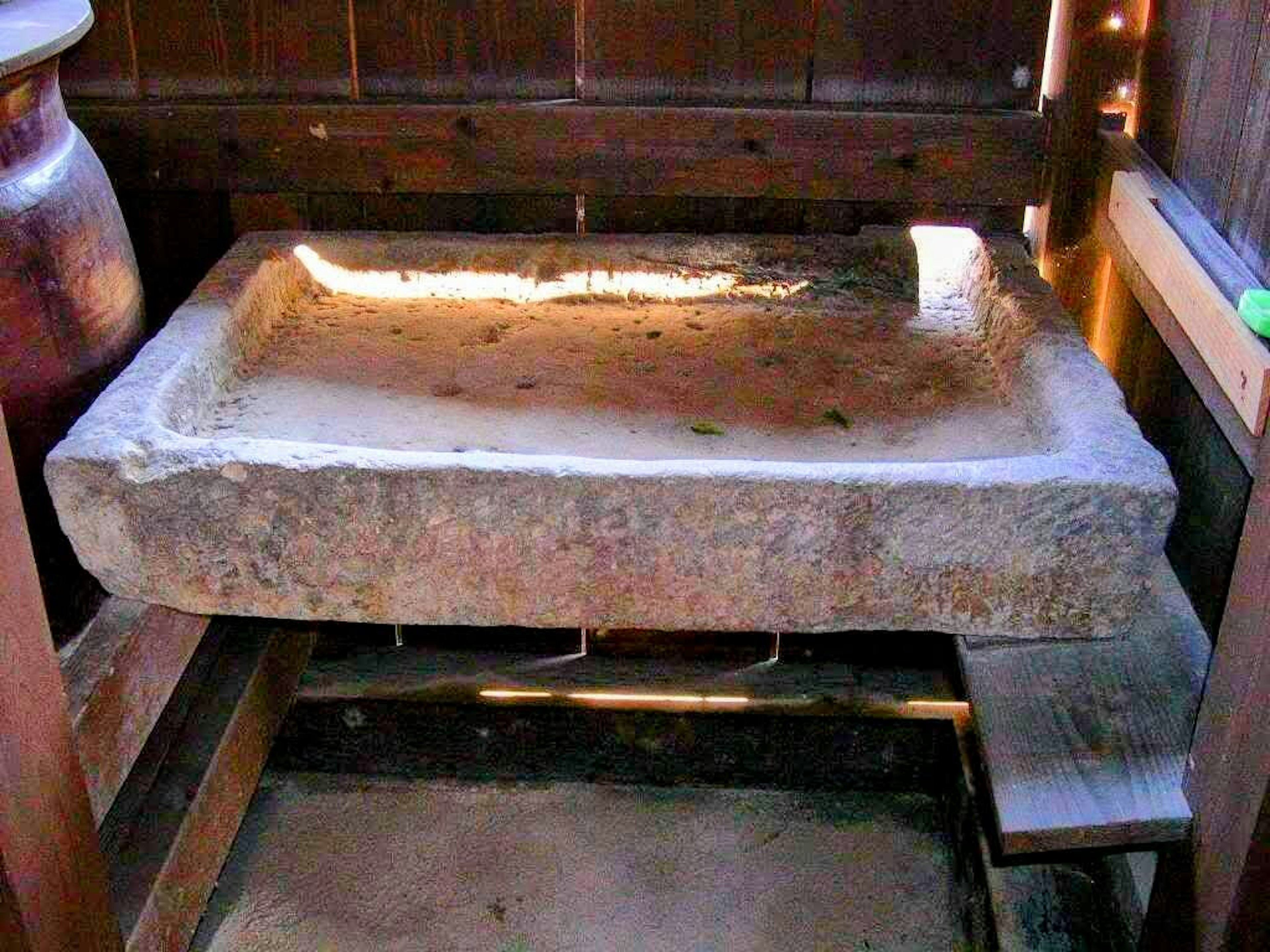 Un ancien lavabo en pierre entouré de murs en bois