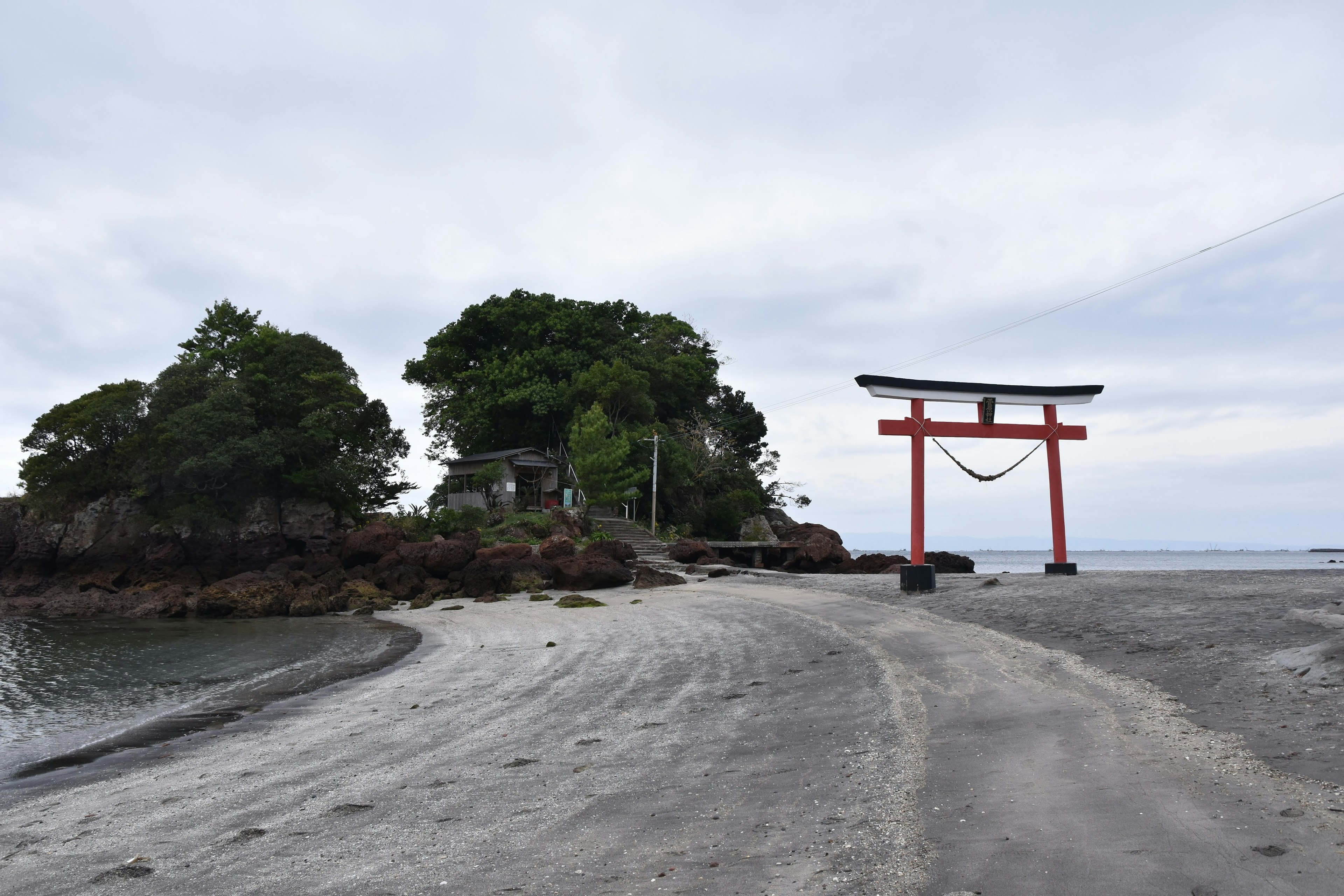 Pemandangan pantai dengan gerbang torii merah dan pulau kecil