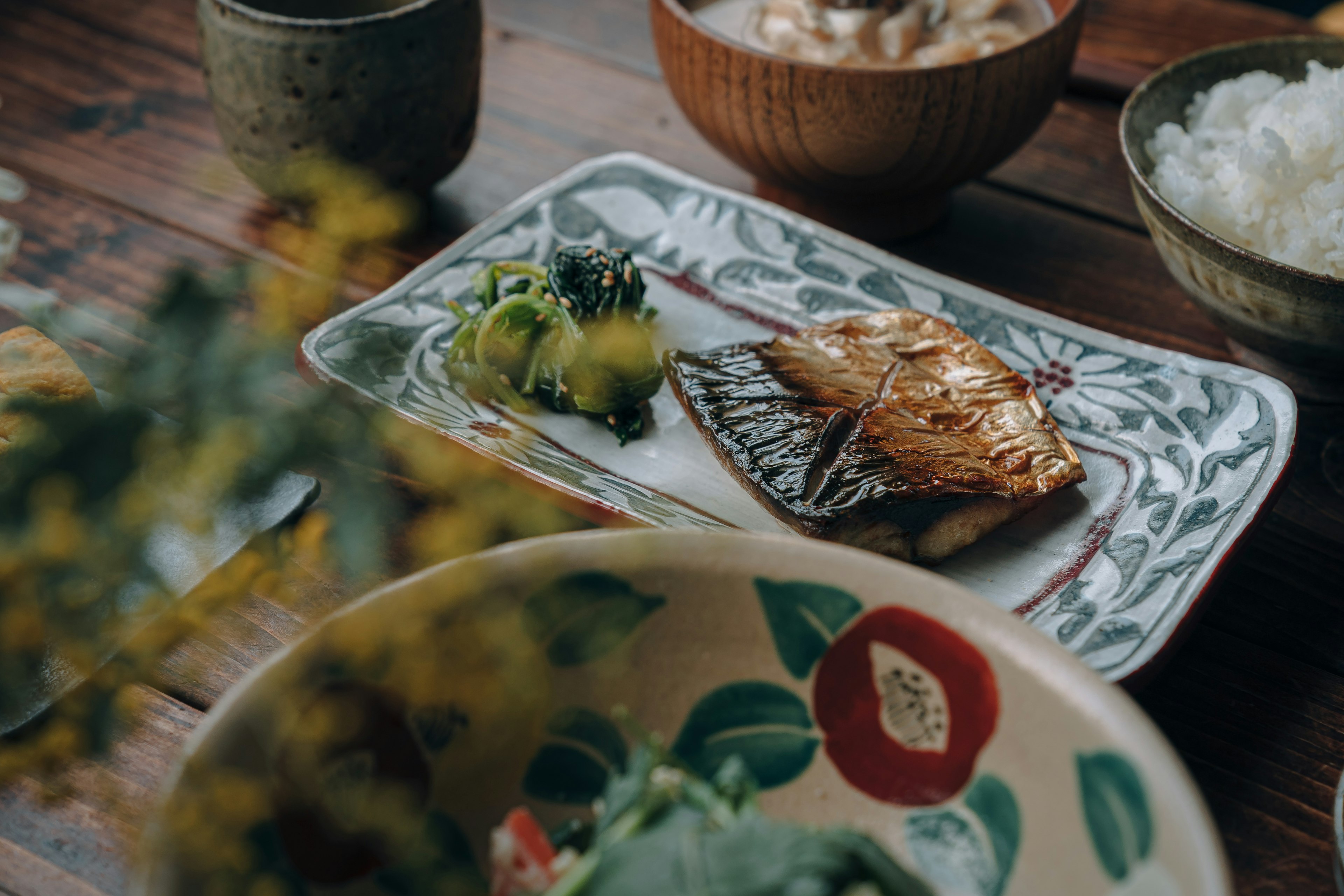 Un piatto ben presentato di pesce grigliato con verdure fresche su un tavolo da pranzo giapponese