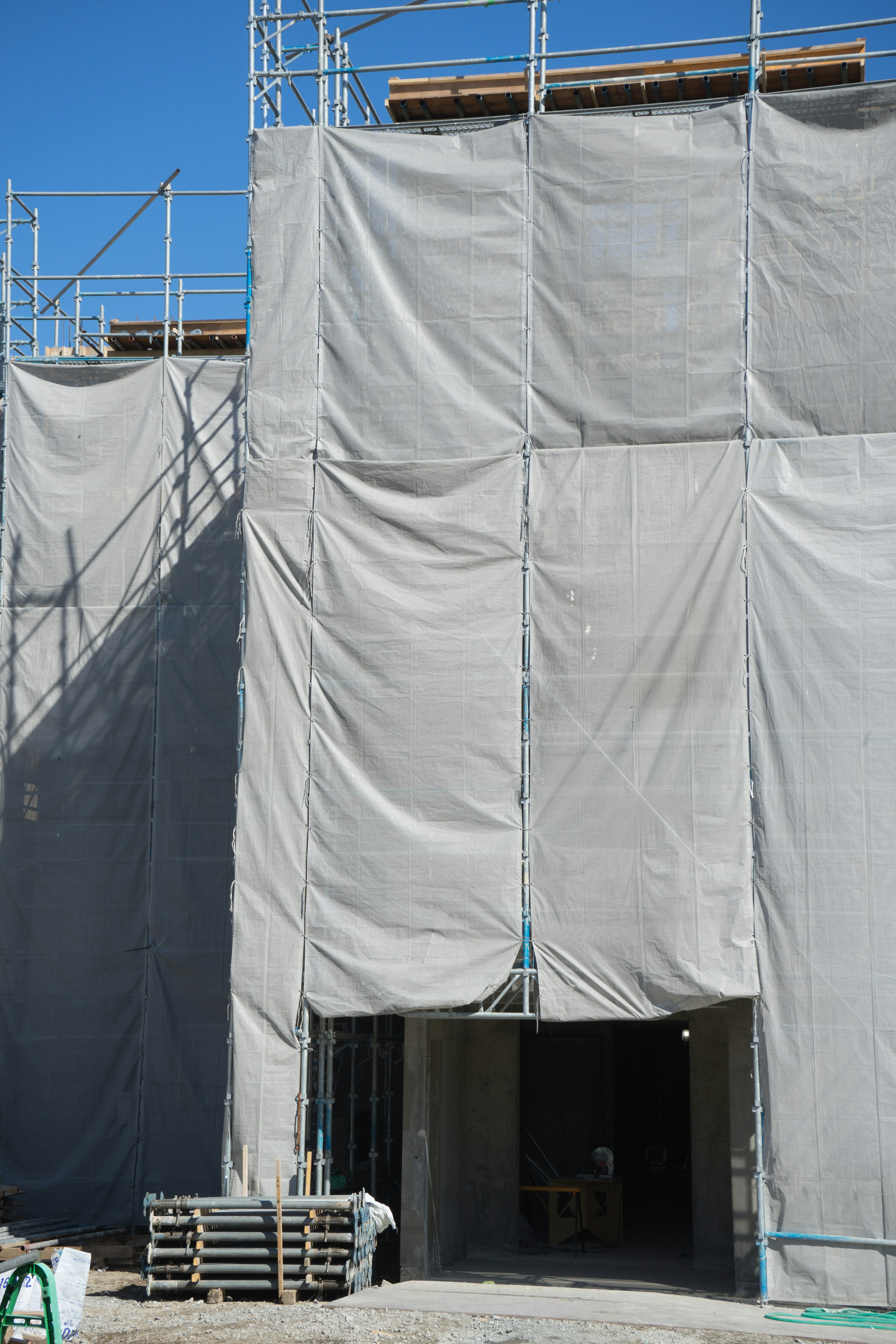 Construction site with scaffolding and covered building facade under blue sky