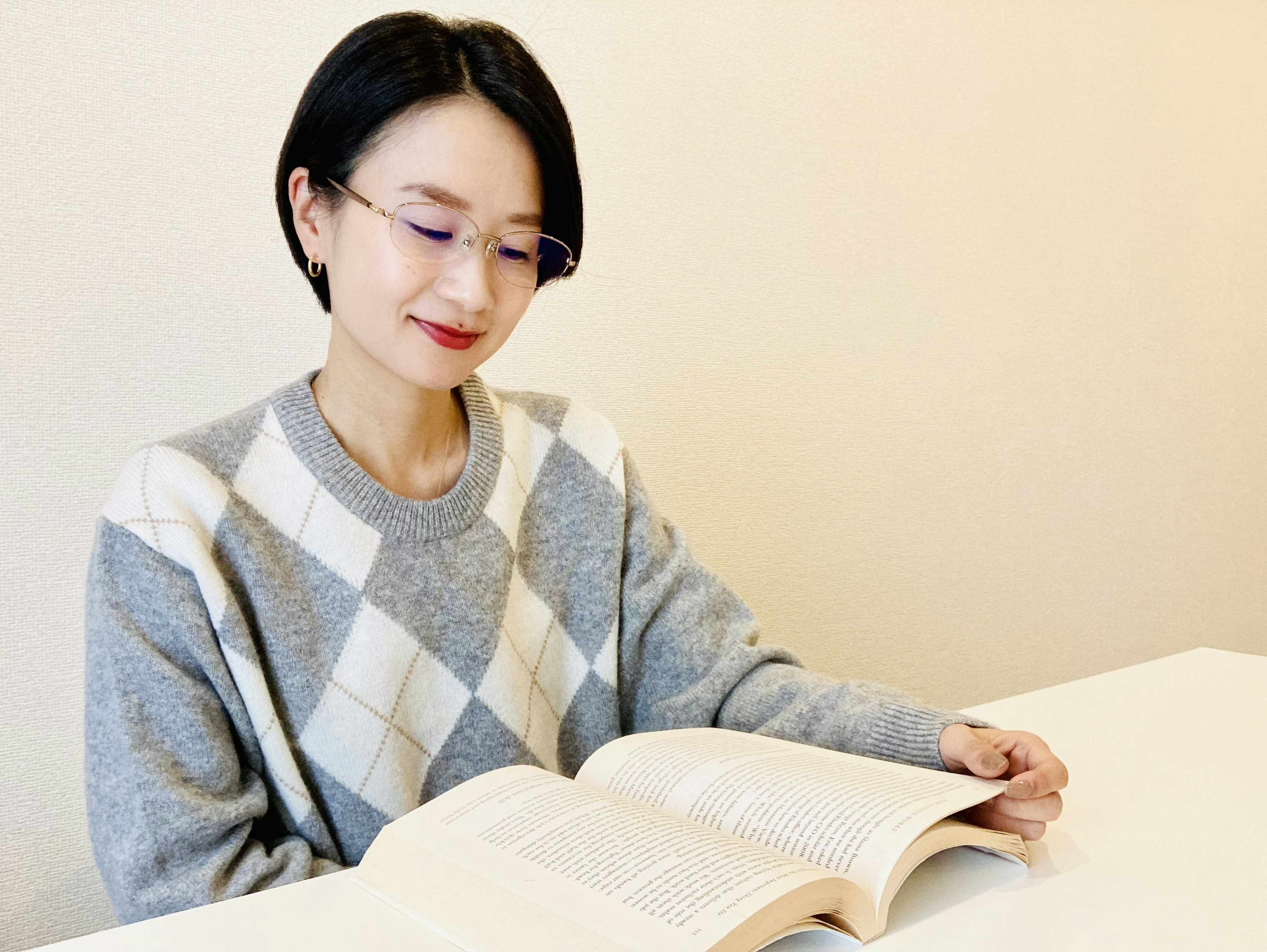 A woman reading a book wearing a gray sweater