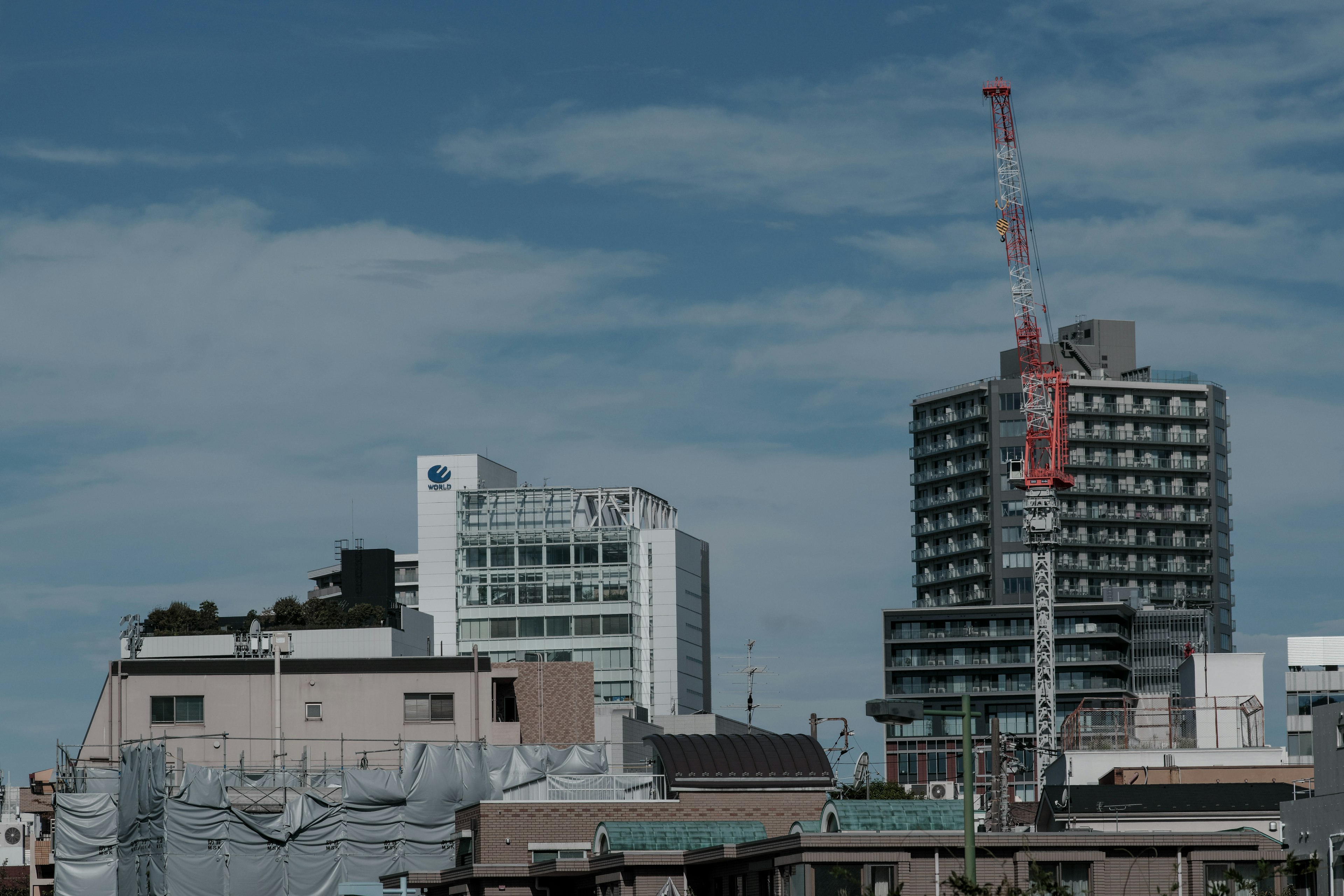 Urban landscape featuring buildings and a crane under a blue sky