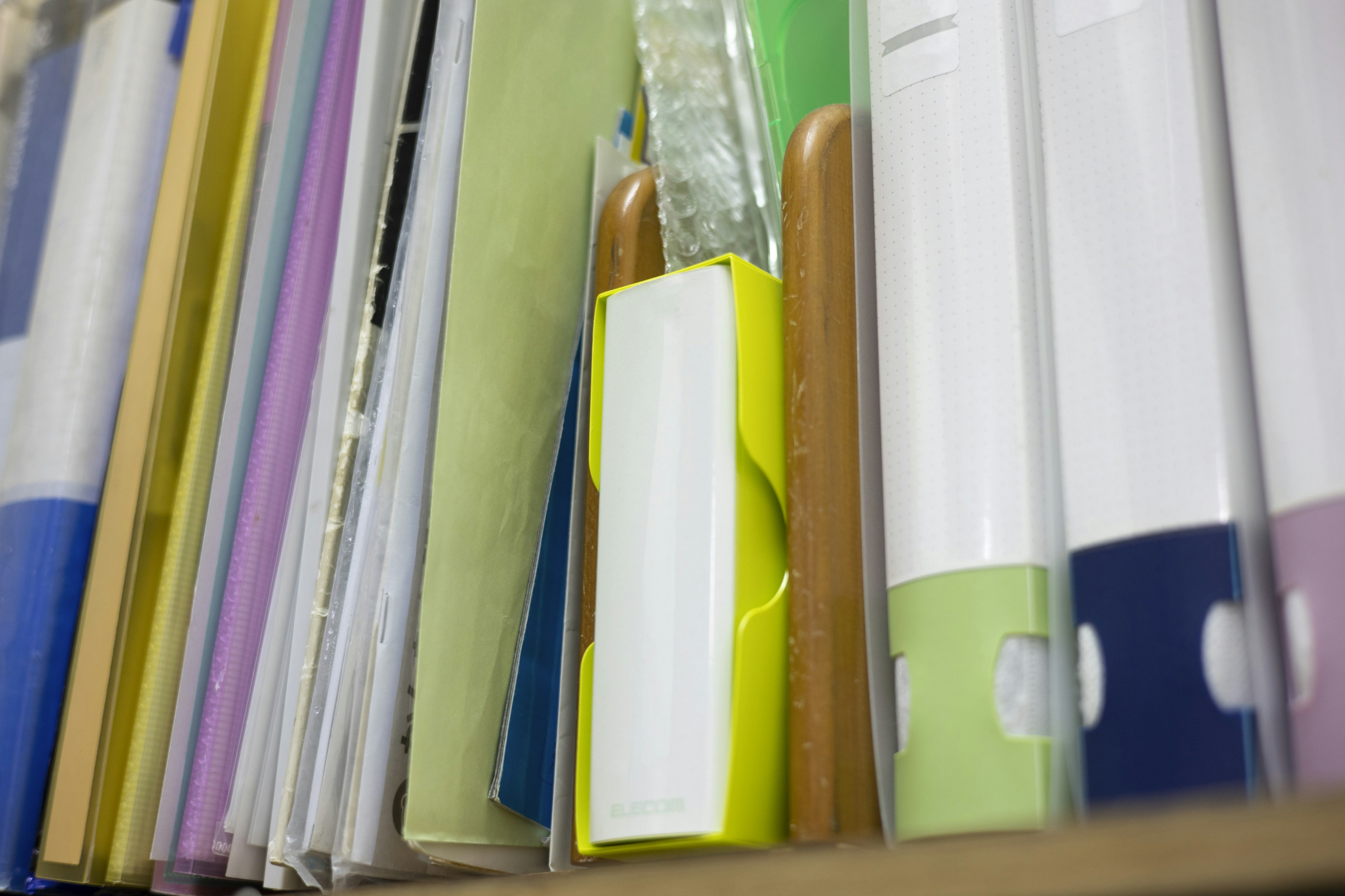 Close-up of a shelf filled with colorful files featuring a prominent yellow file in the center