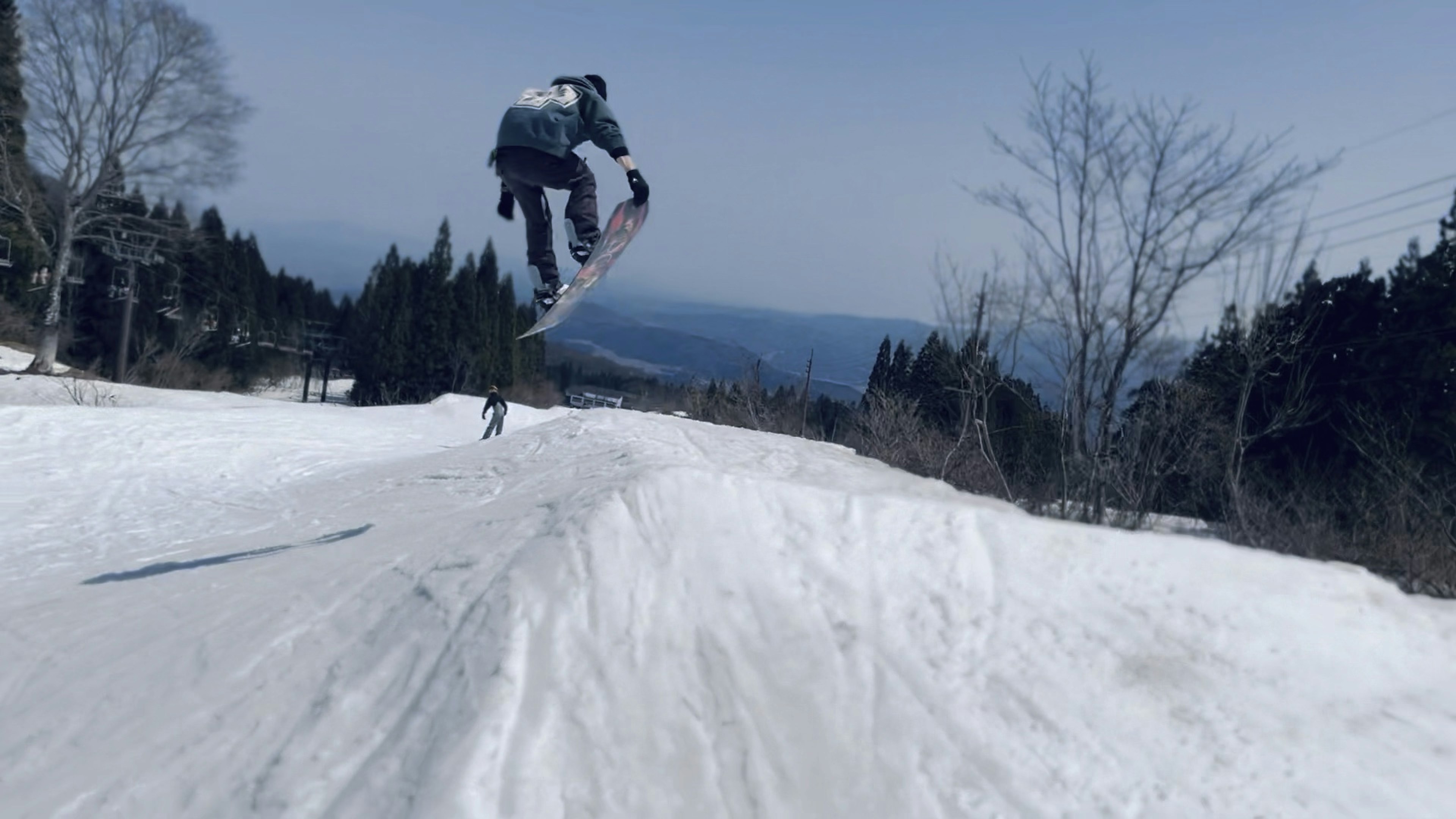 Ein Snowboarder springt im Schnee mit einem bergigen Hintergrund