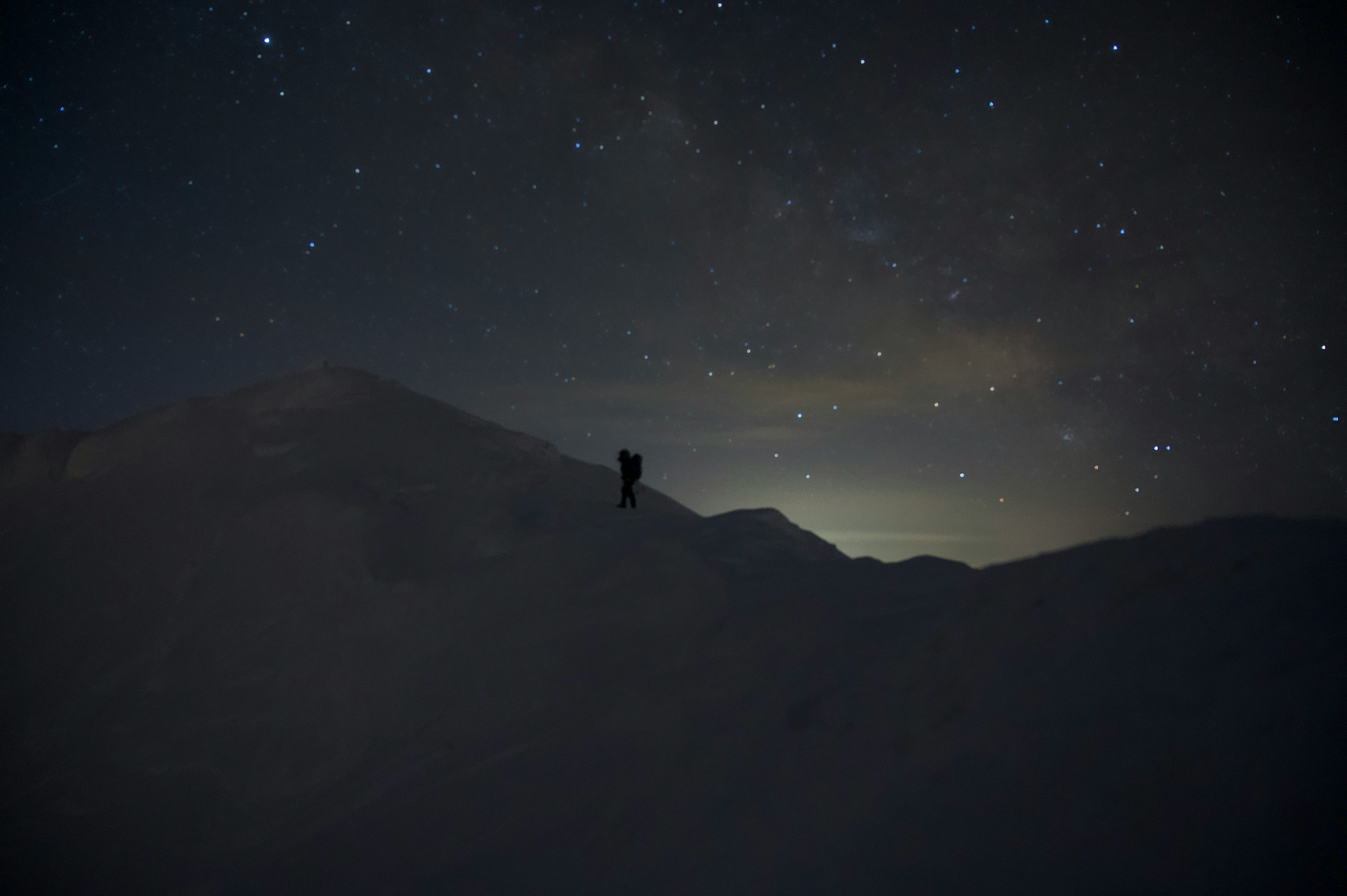 雪山の夜空に輝く星々とシルエットの登山者