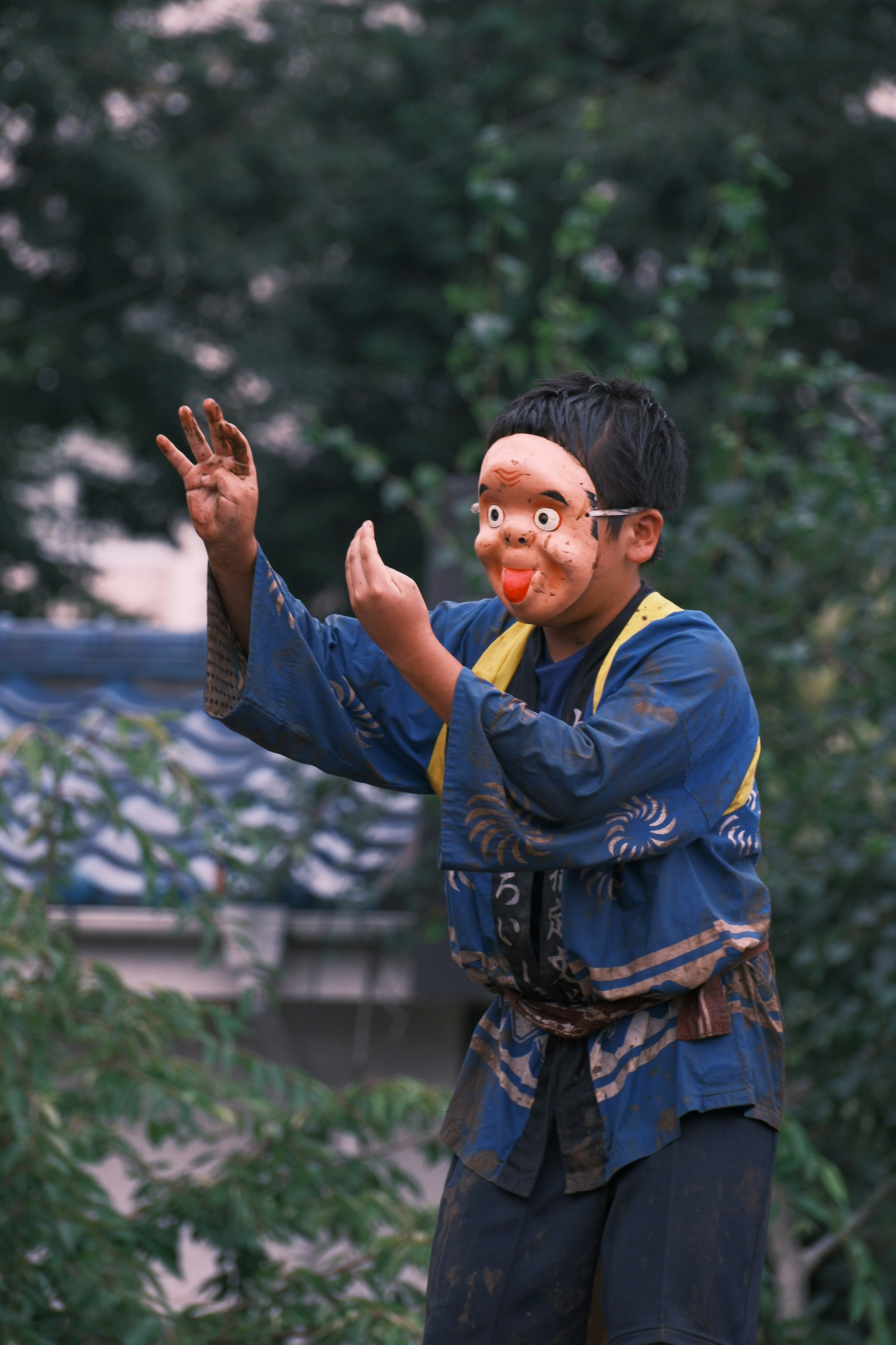 一个穿着传统日本服装的男孩戴着面具表演