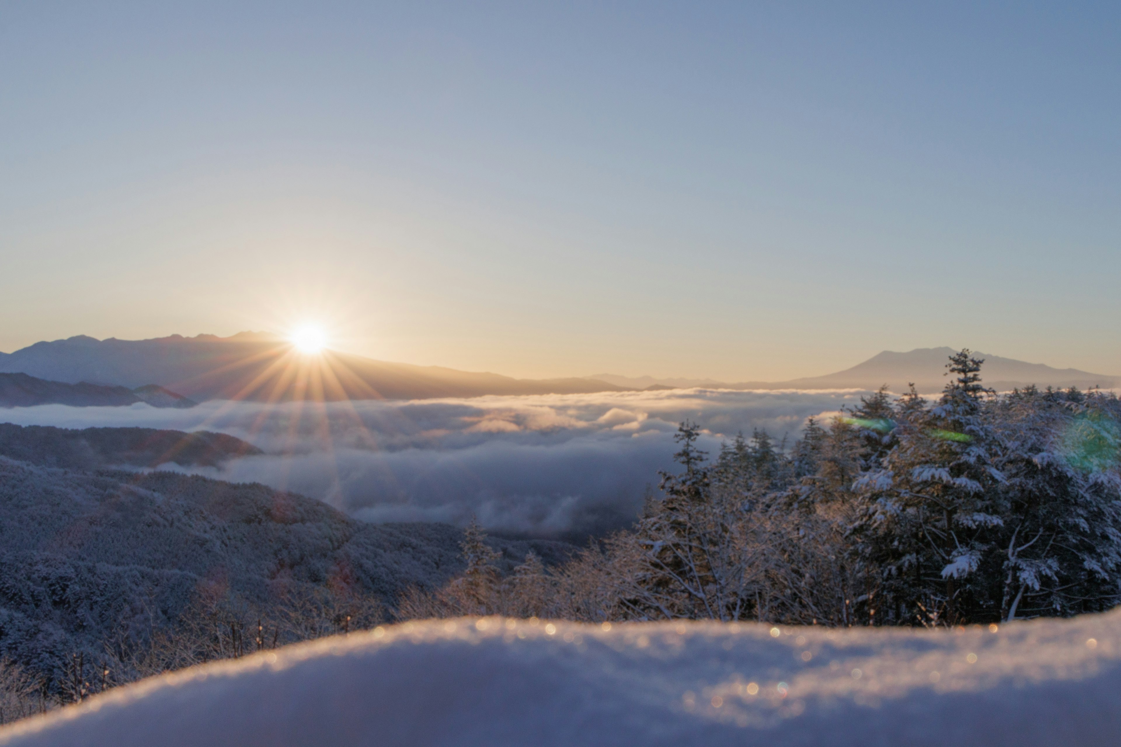 Amanecer sobre montañas cubiertas de nieve y mar de nubes