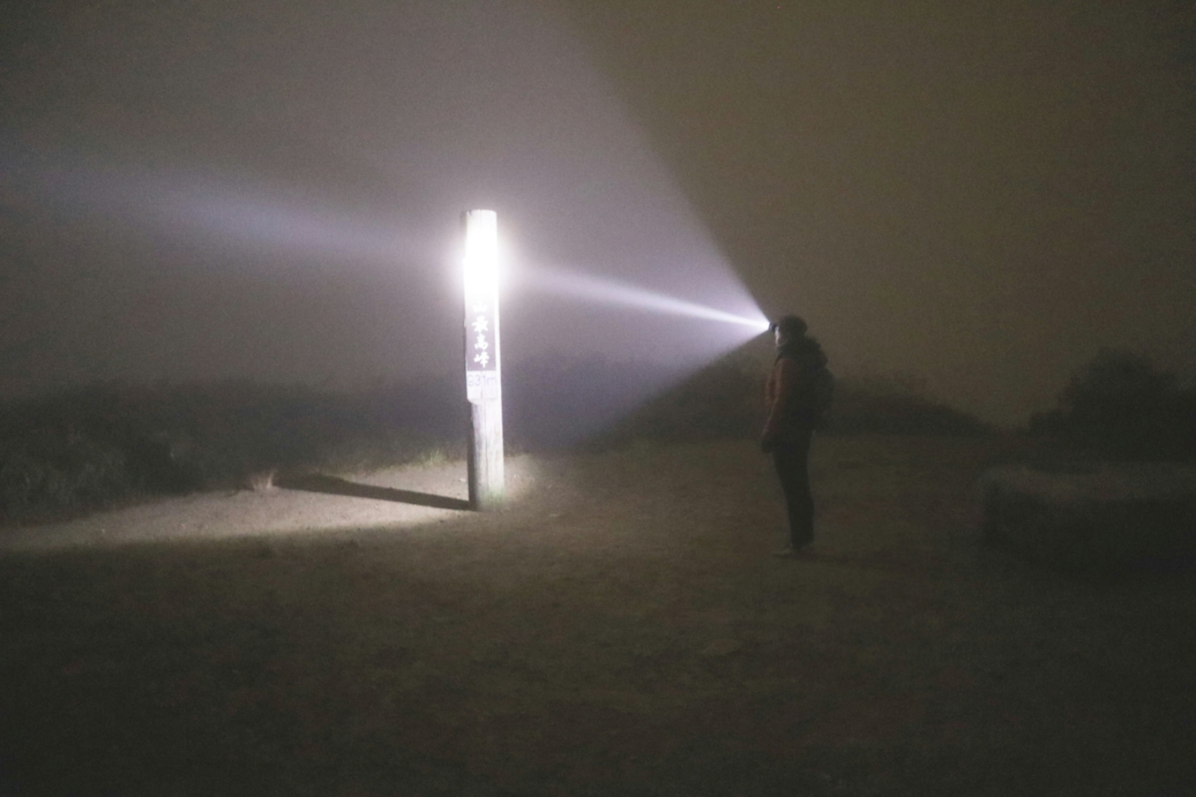 Person holding a flashlight in fog with a bright beam of light