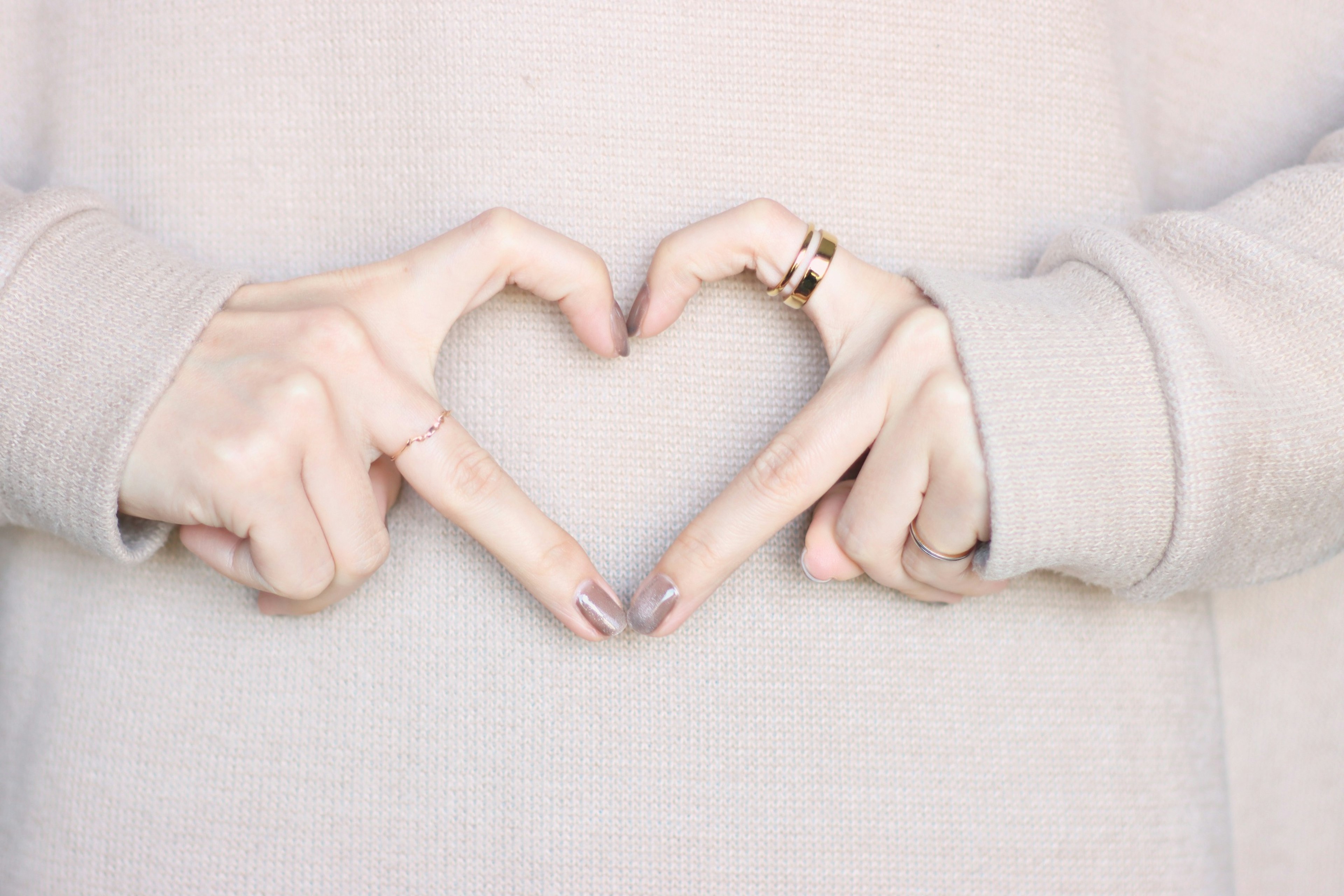 Mani che formano una forma di cuore con colori tenui