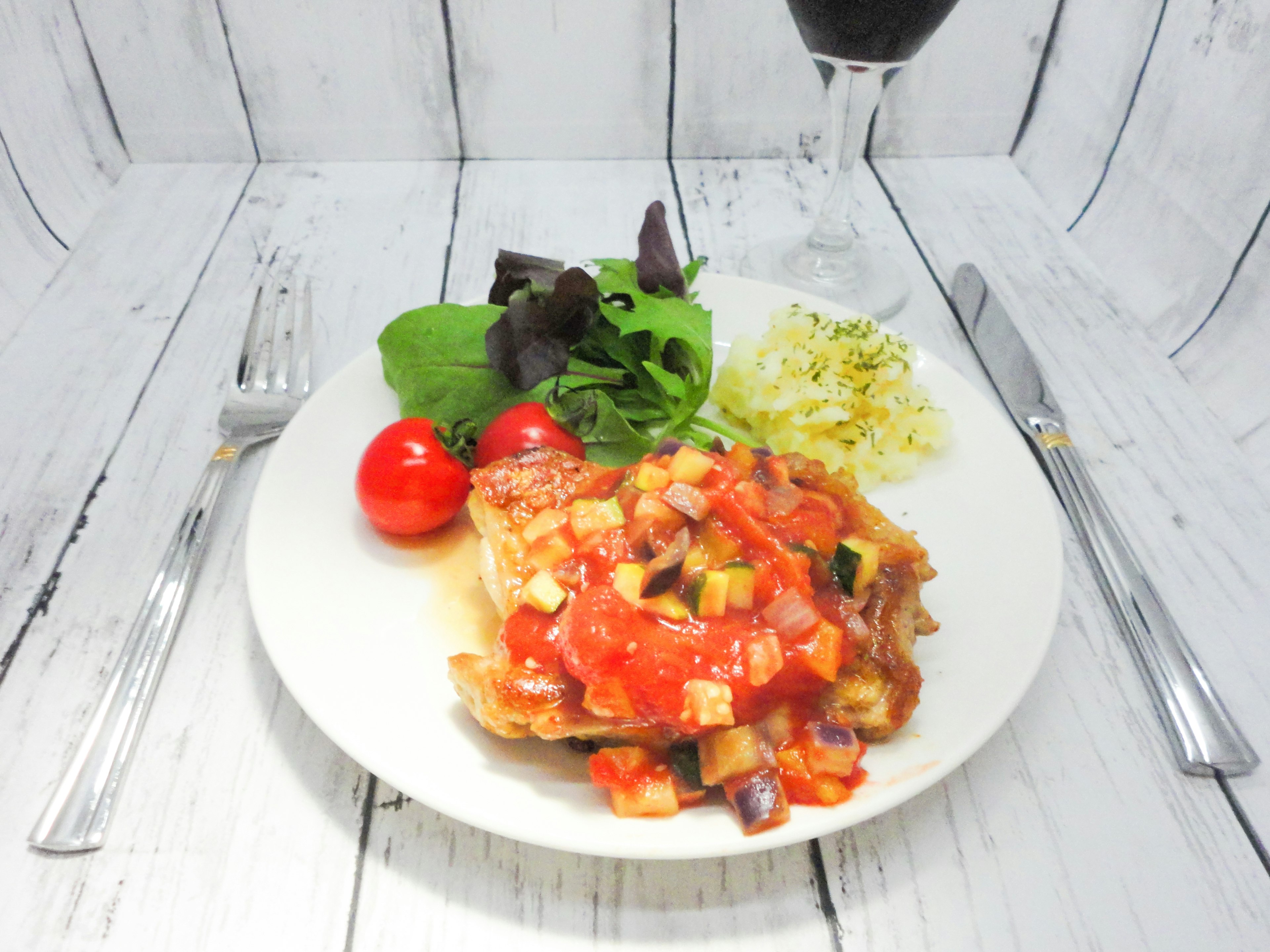 Pasta mit Tomatensauce auf einem weißen Teller mit Salat und Kirschtomaten