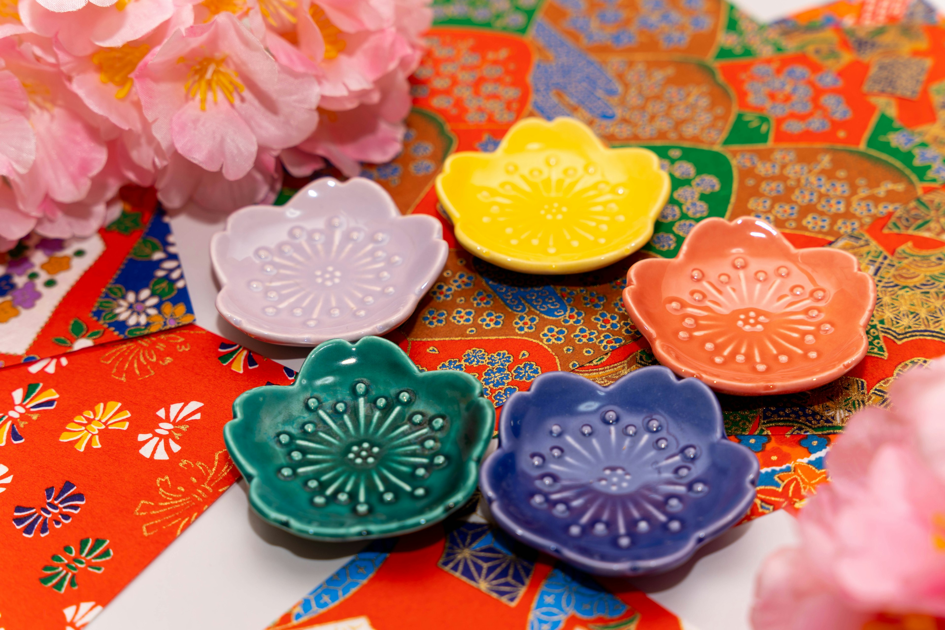 Colorful flower-shaped dishes arranged on a vibrant patterned fabric background