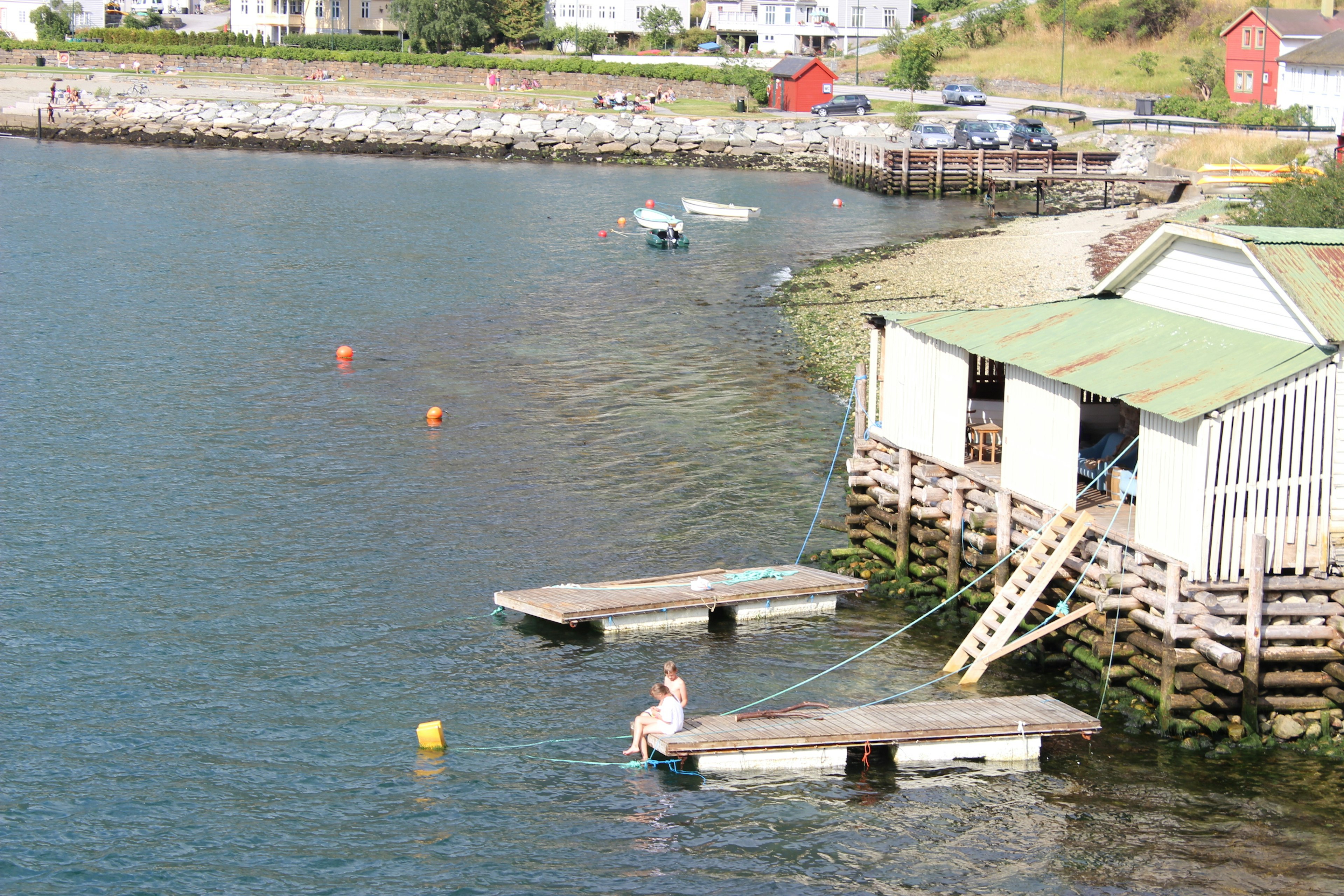 Eine Person entspannt sich auf einem Steg neben einem Bootshaus am Wasser