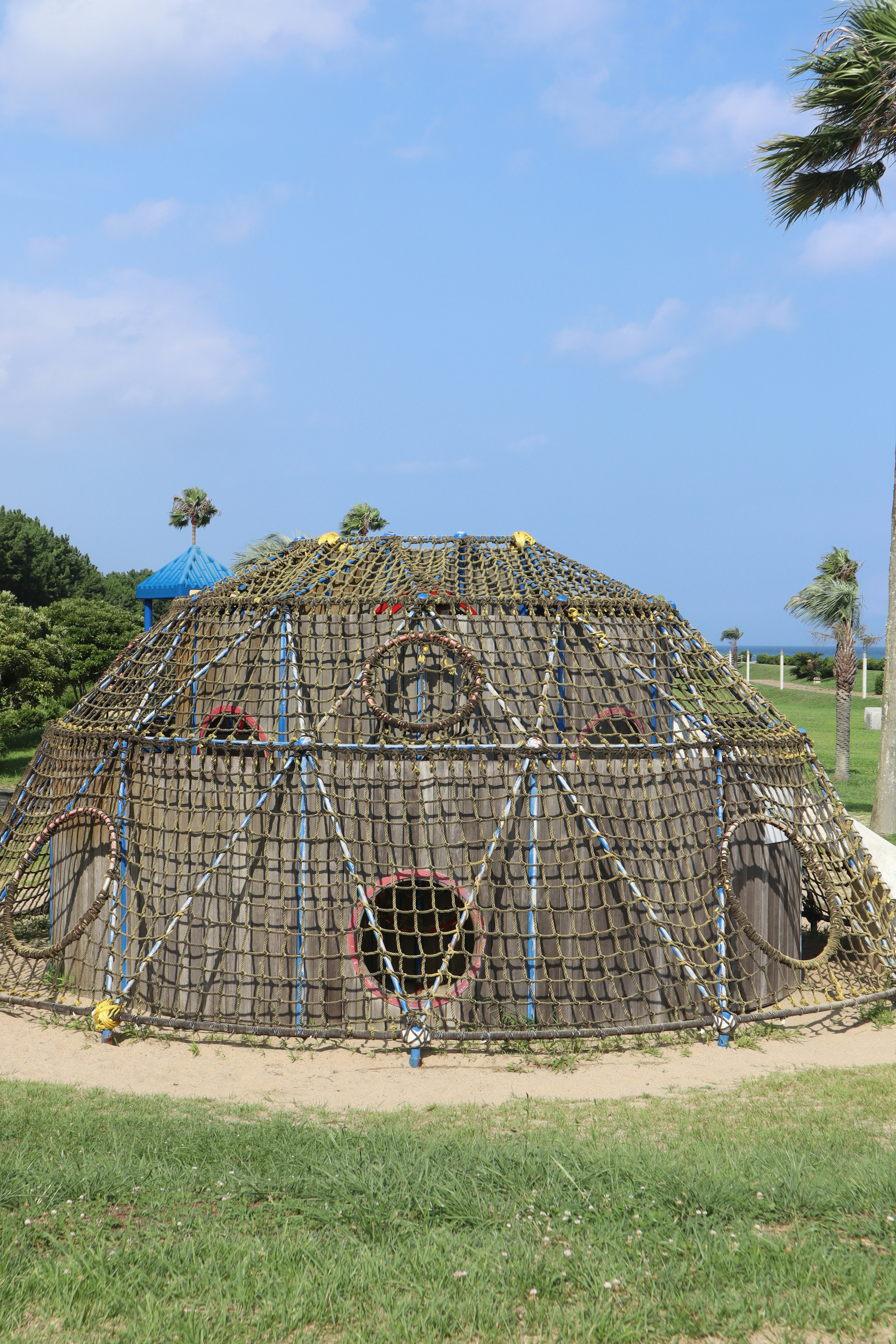 Round straw structure under blue sky with green grass around