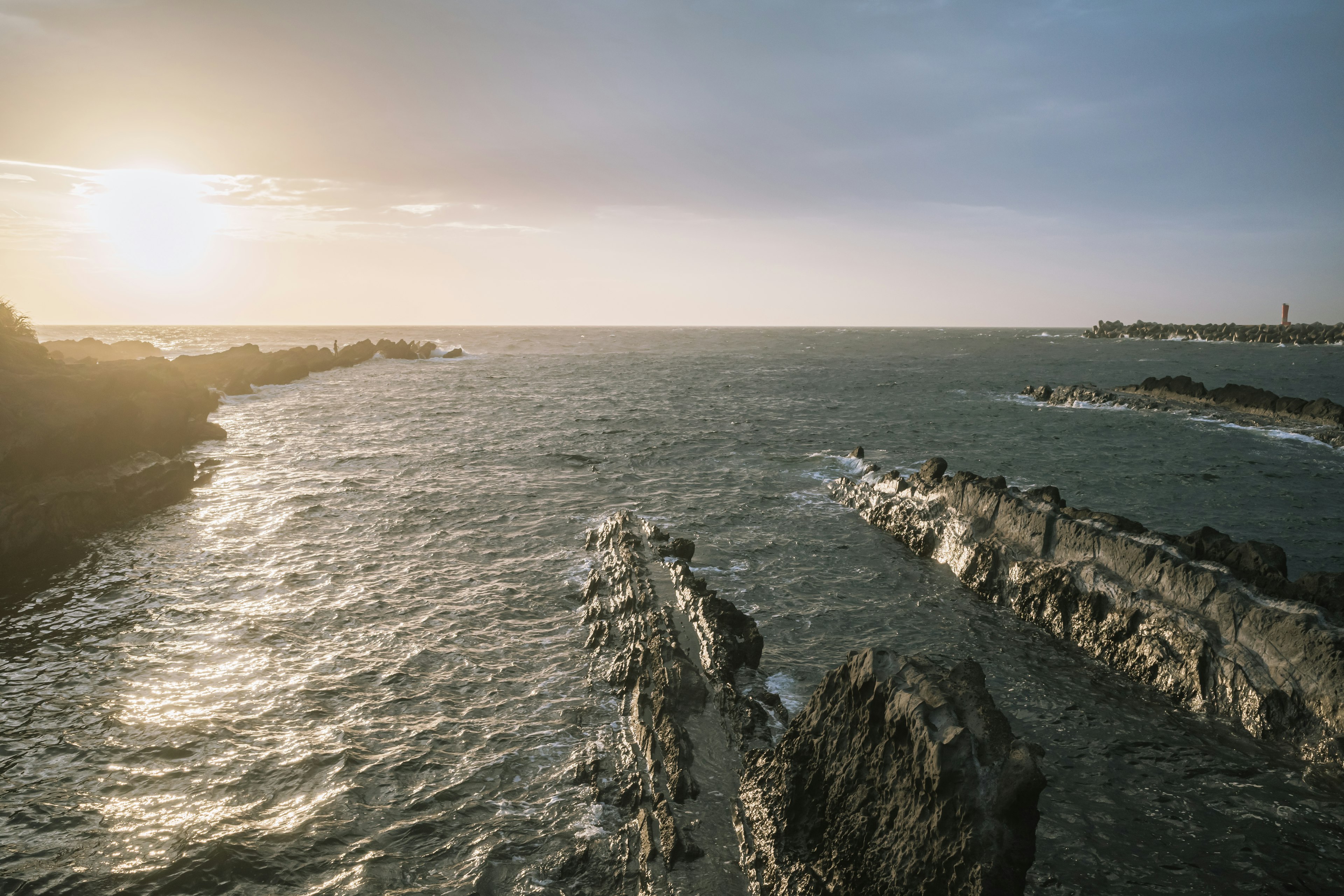 Paisaje costero con línea de costa rocosa y atardecer