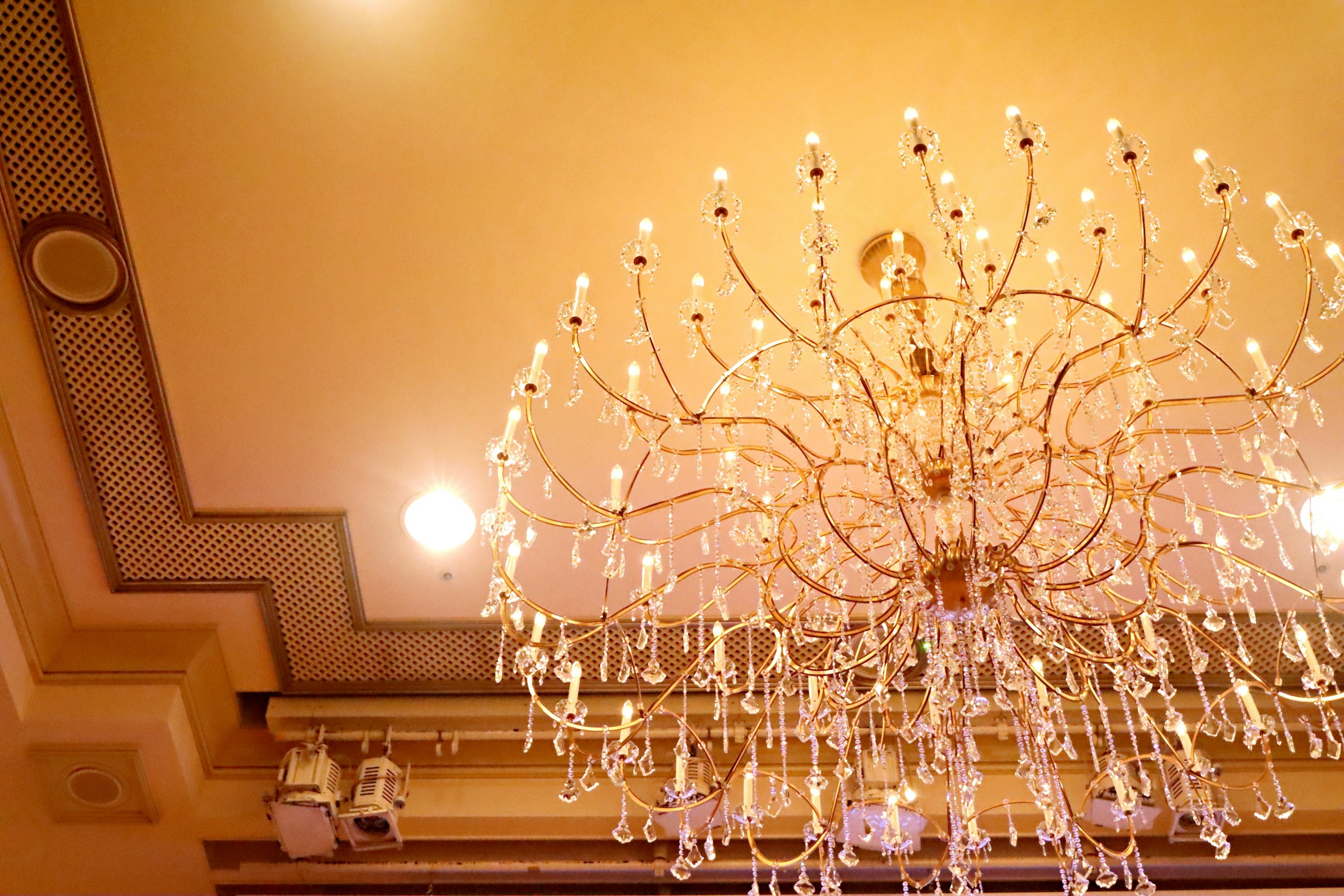 Elegant chandelier hanging from a ceiling with warm yellow tones