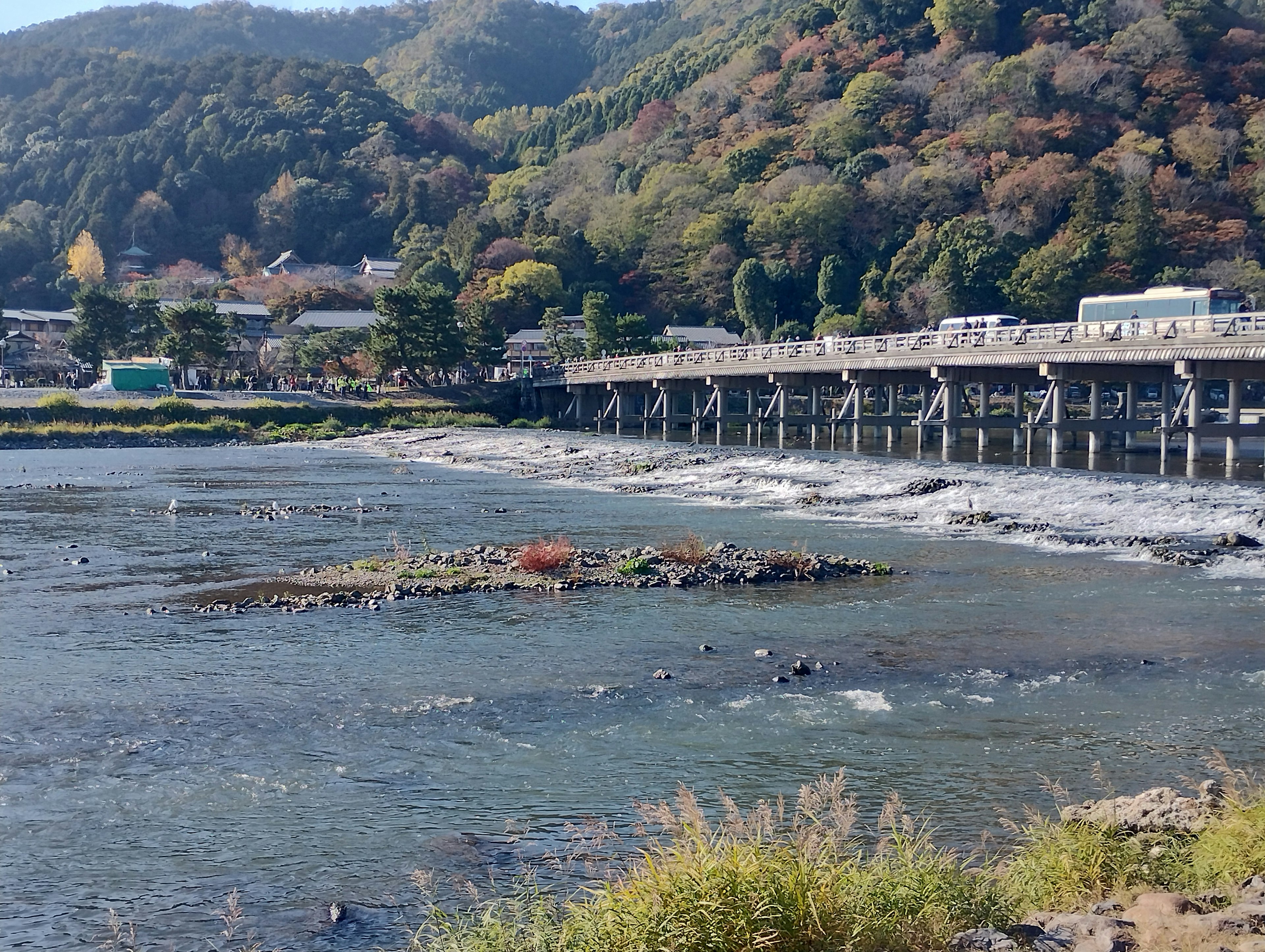 Scenic view of a river with a wooden bridge and autumn foliage on the hills