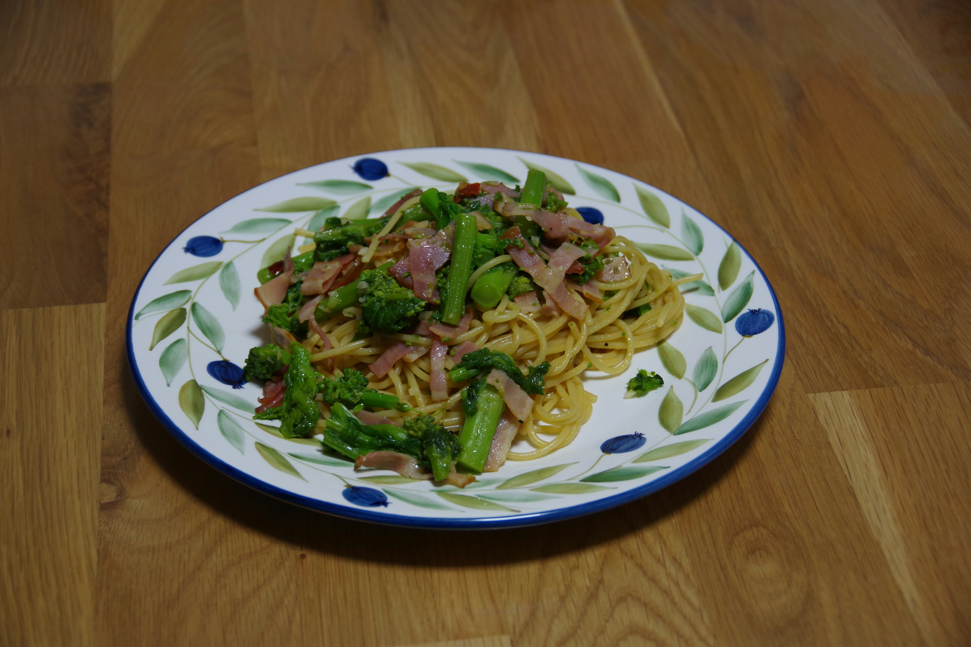 Spaghetti topped with colorful vegetables and ham on a decorative plate