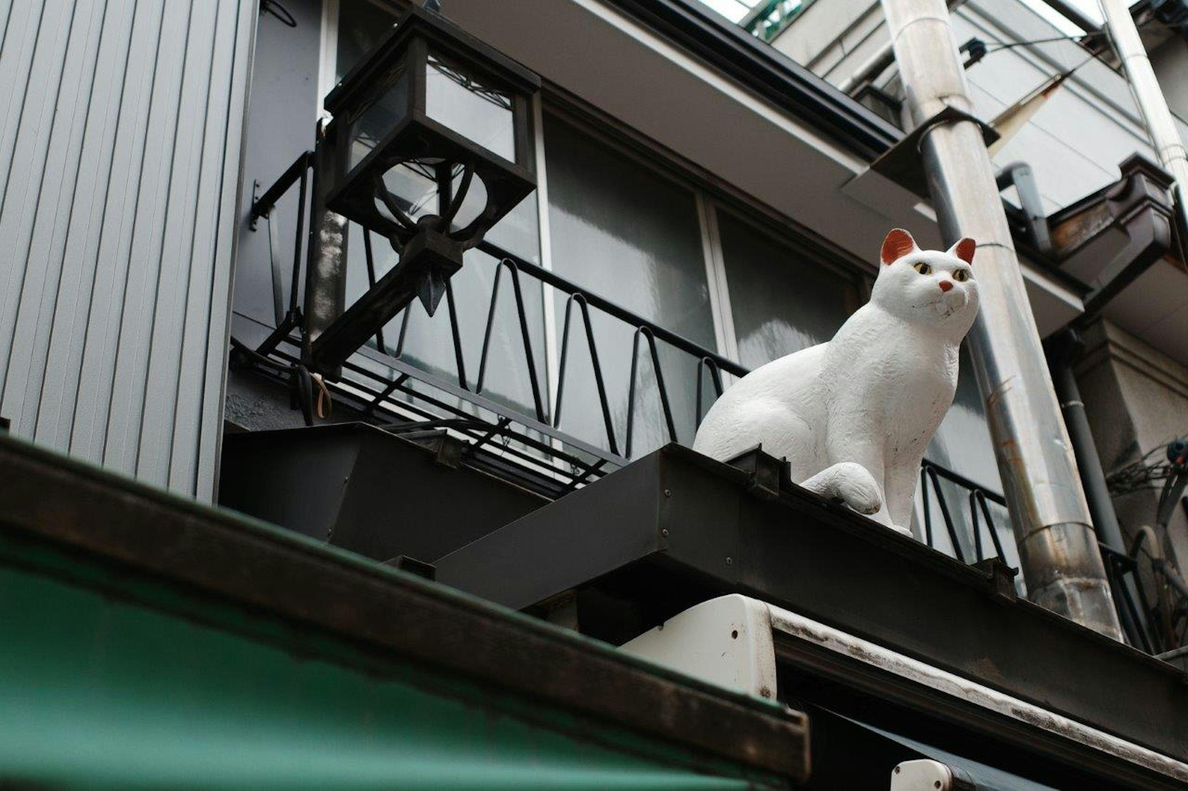 A white cat sculpture is perched on a balcony