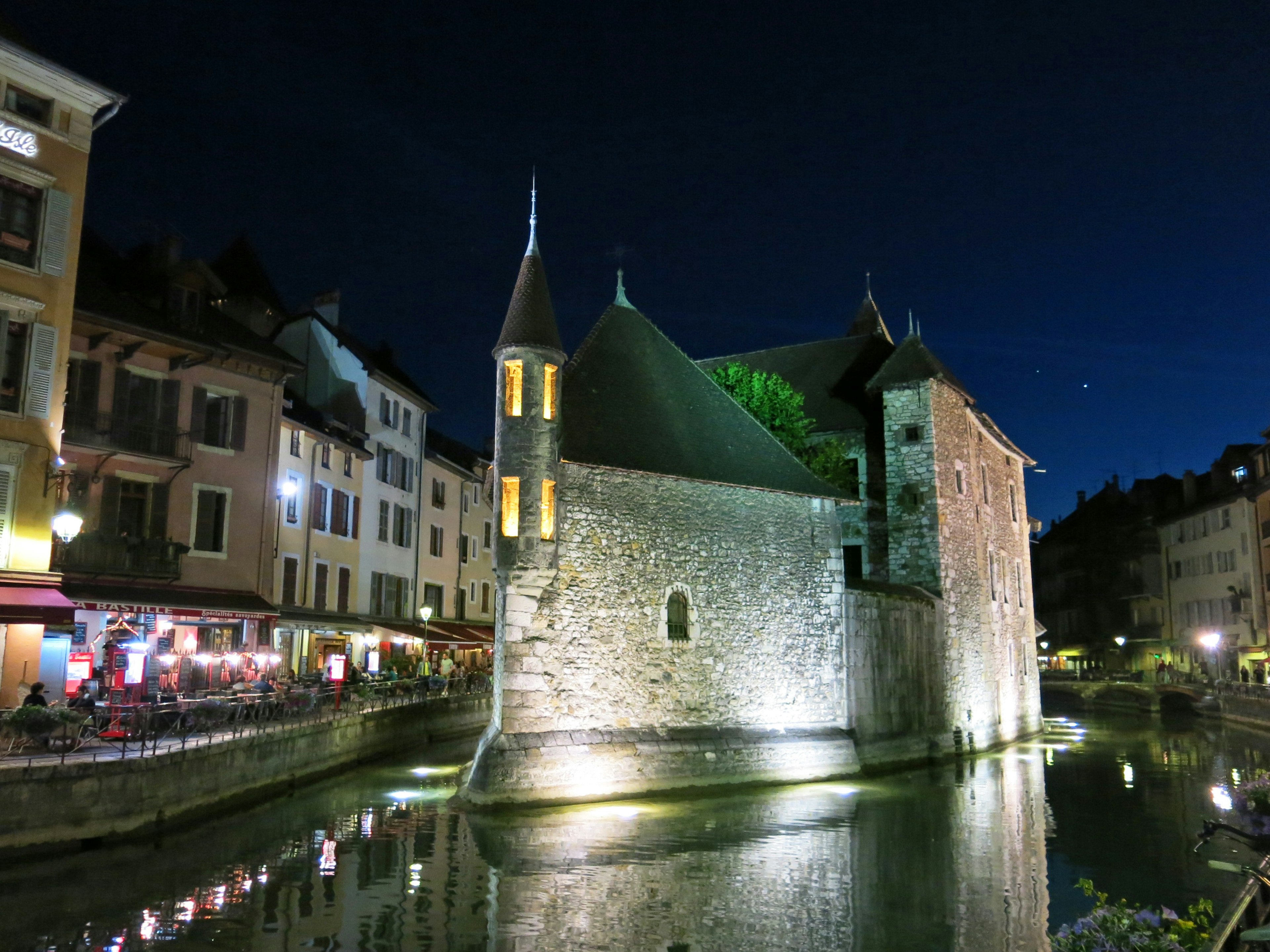 Bâtiment en pierre au bord du canal à Annecy la nuit