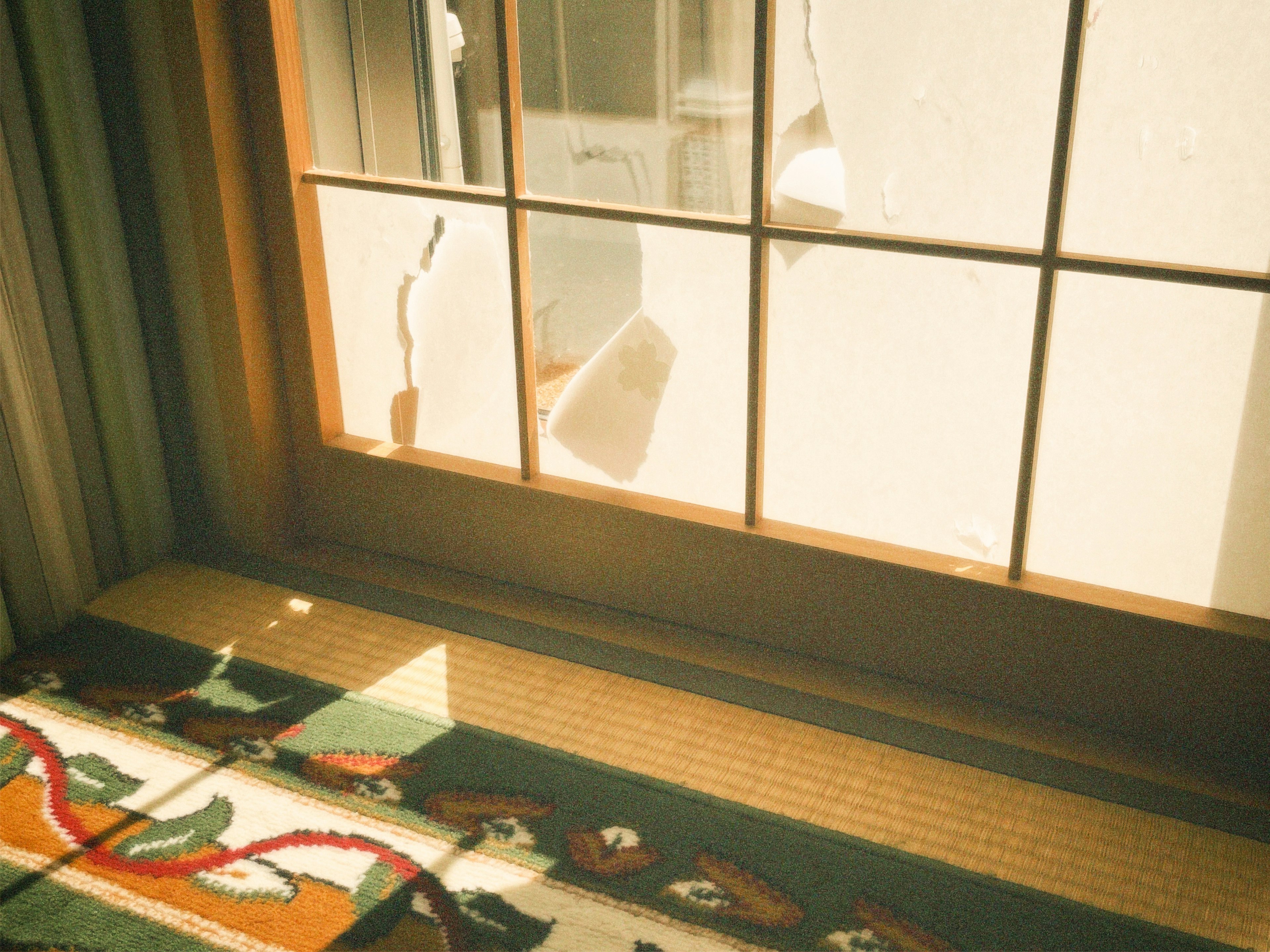 Sanftes Licht, das durch ein traditionelles japanisches Fenster strömt, mit einem schönen Teppich im Vordergrund