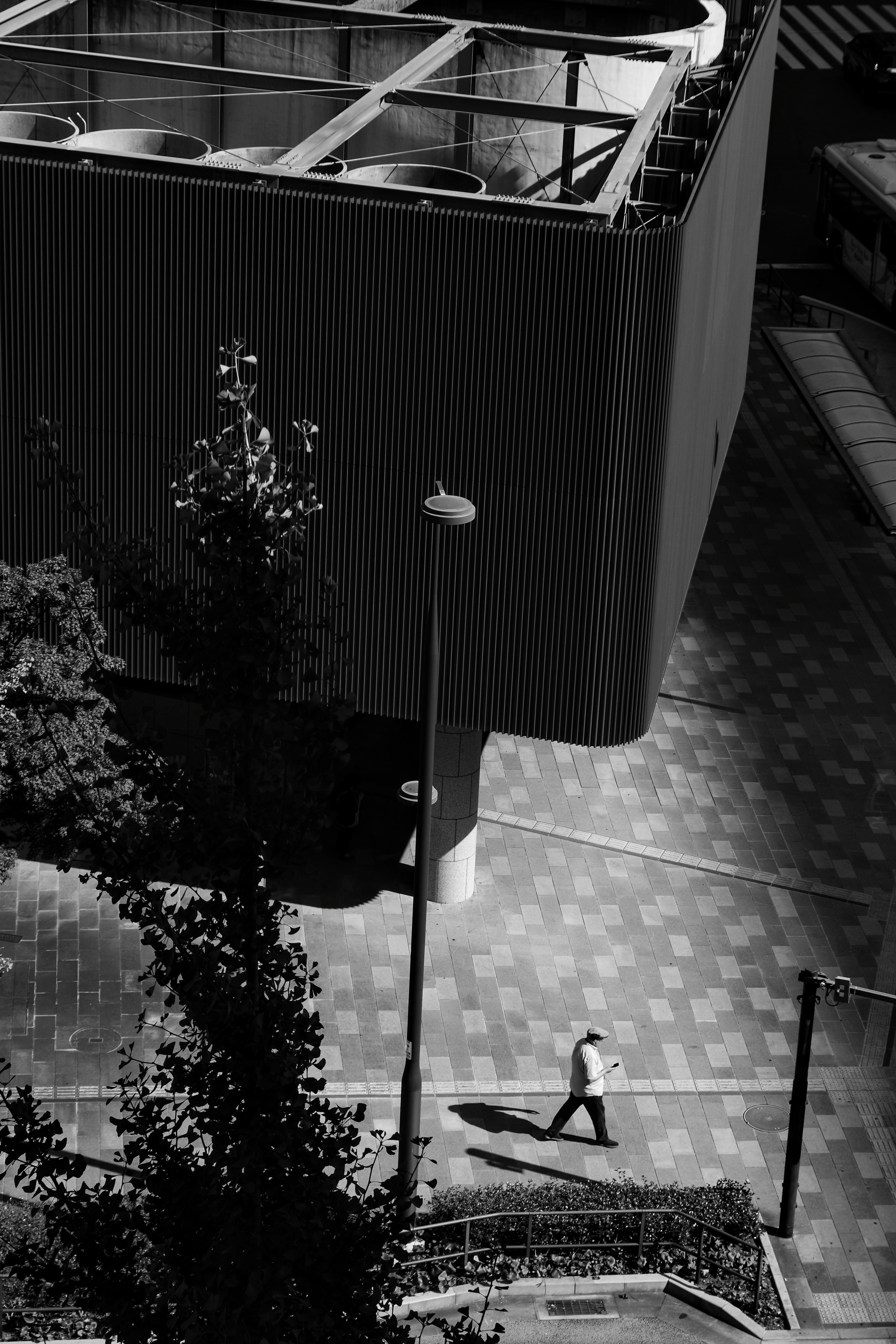 Una persona caminando en un paisaje urbano en blanco y negro con un edificio moderno