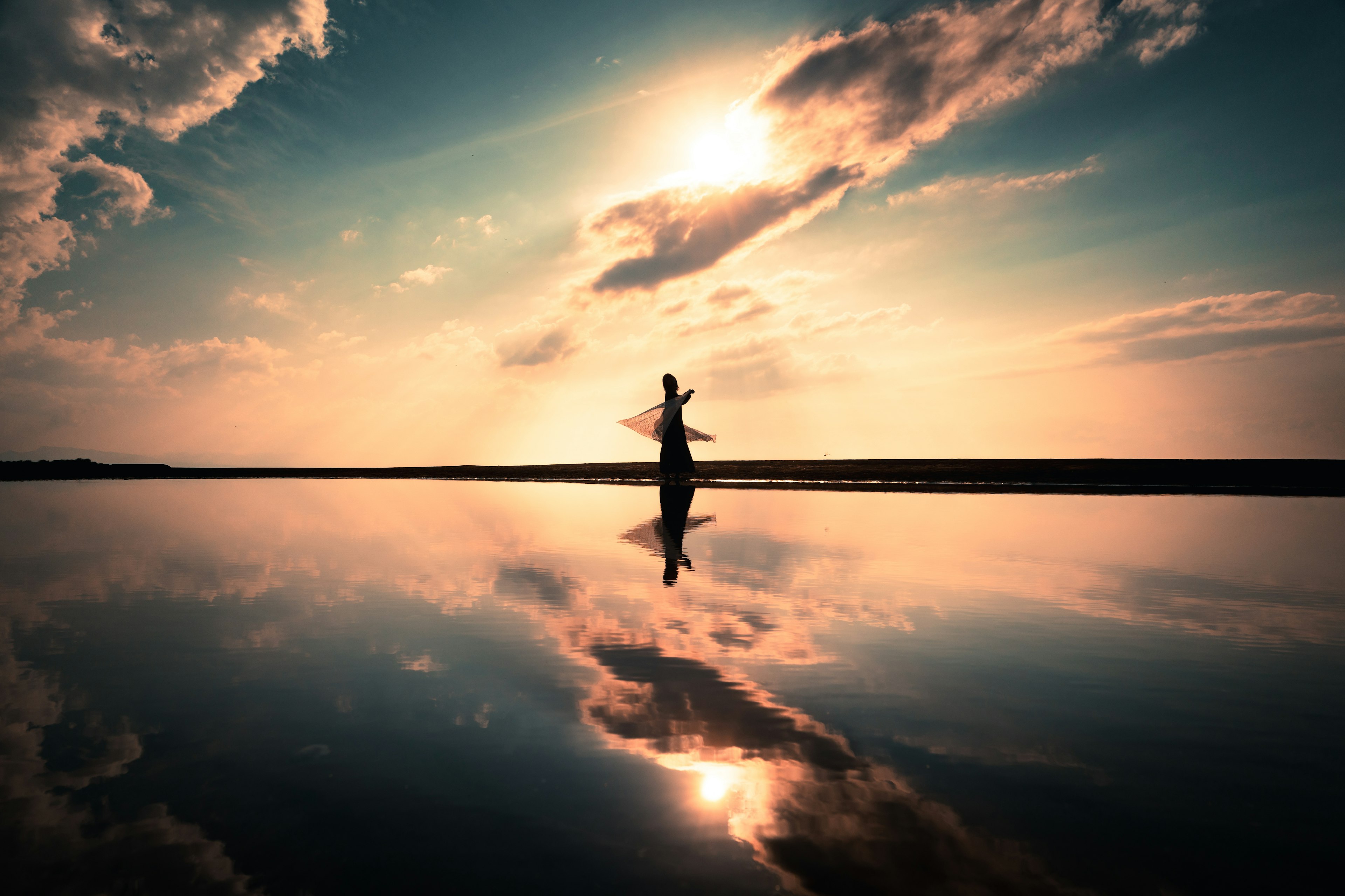 Silueta de una mujer de pie contra un hermoso atardecer con reflejo