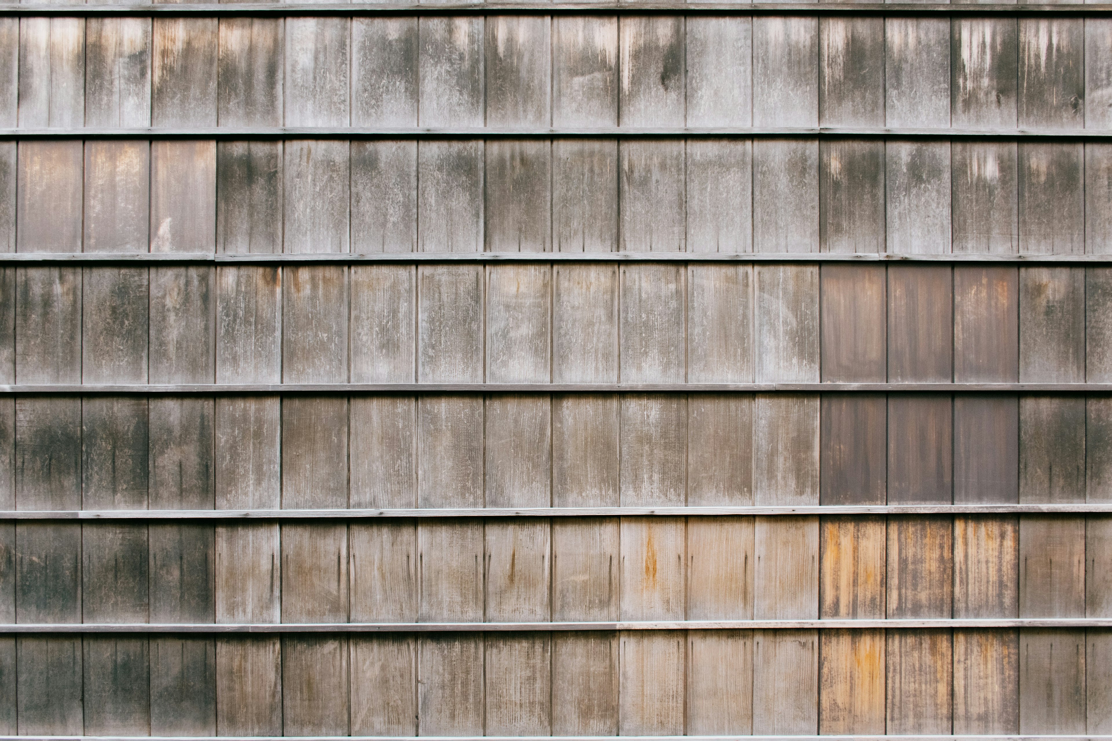 Textured surface of an old metal wall showing rust and faded sections