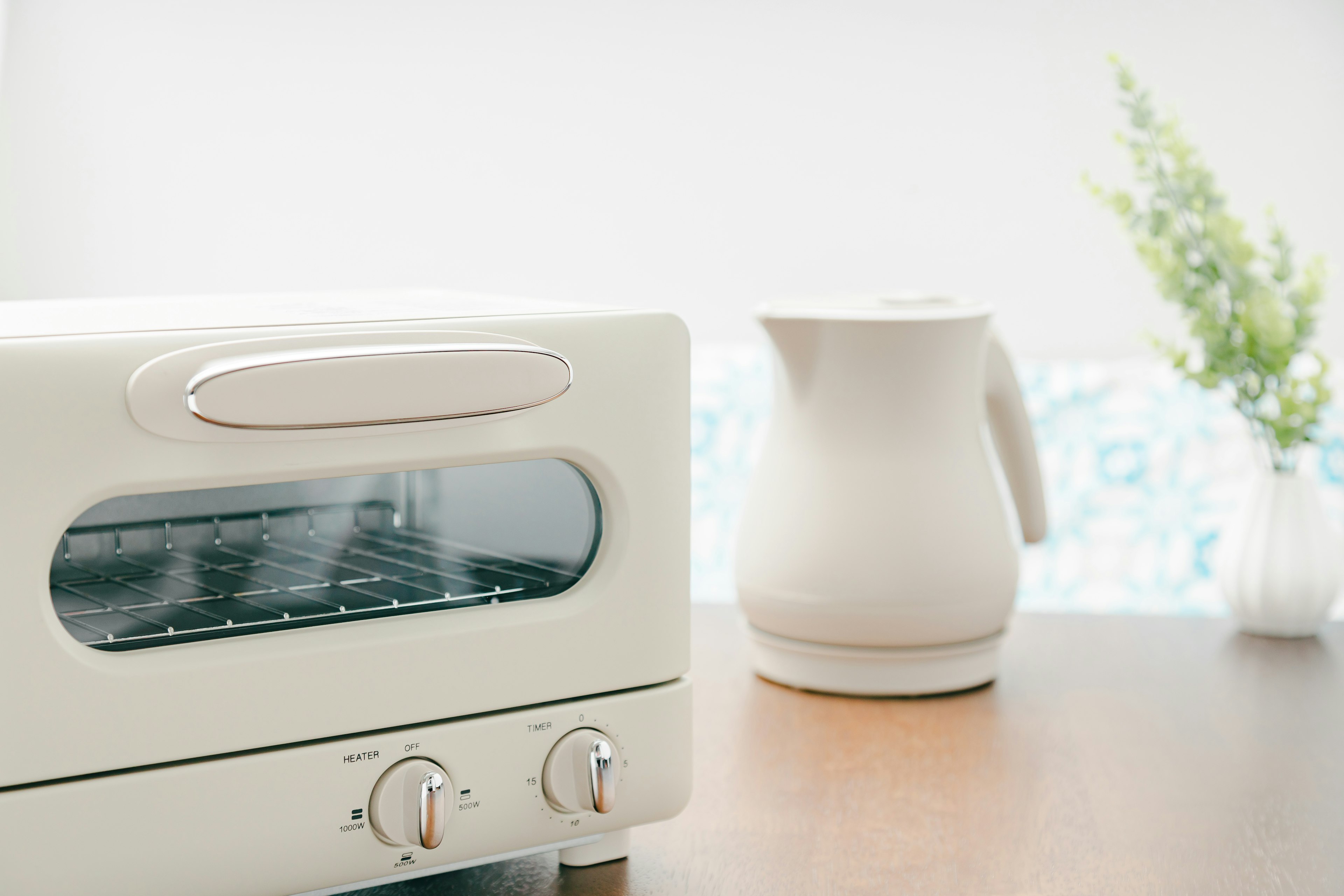 Un grille-pain blanc et une bouilloire blanche sur une table en bois dans un cadre de cuisine simple