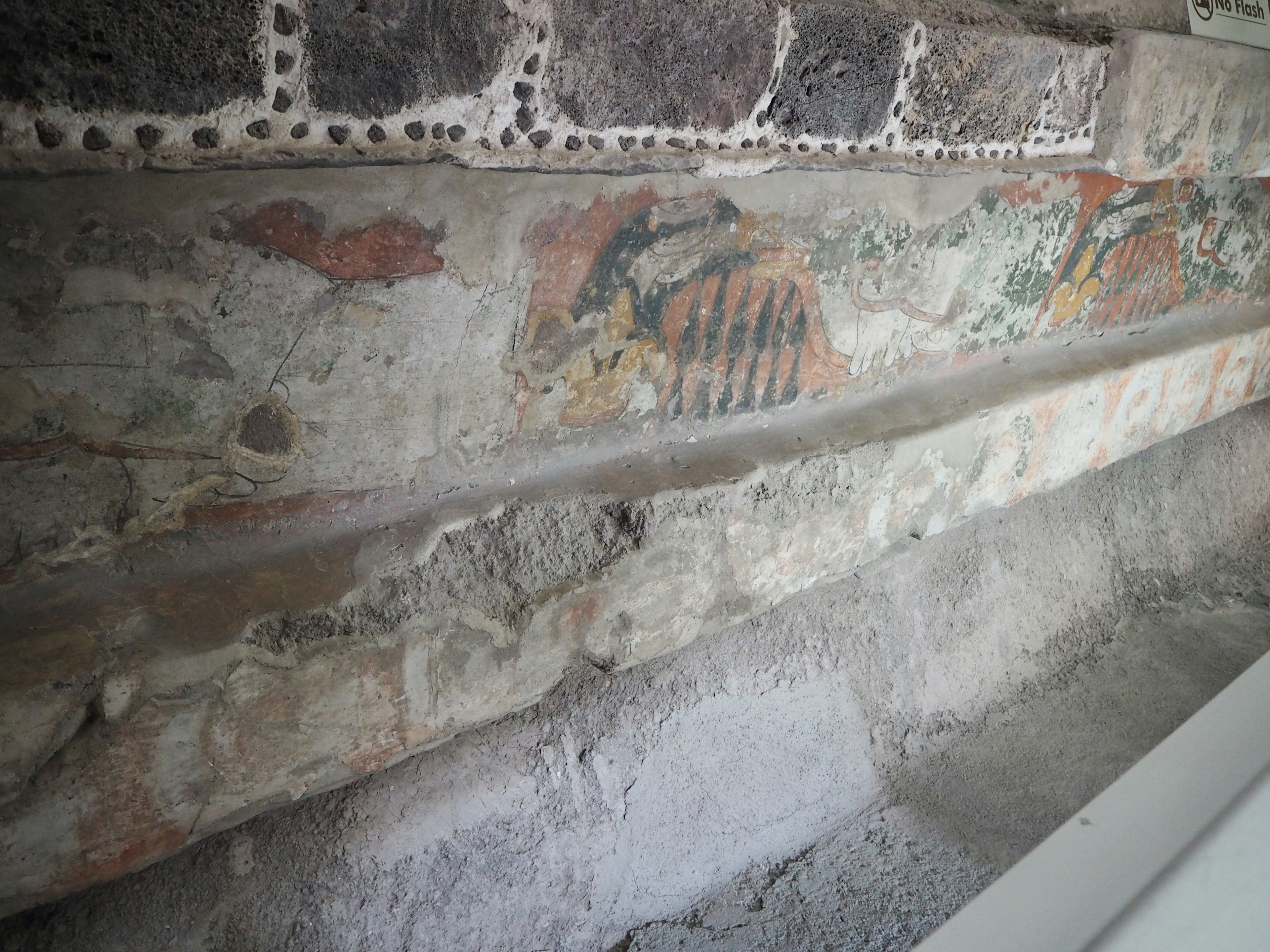 Sección de una antigua pared de piedra con pinturas murales desvanecidas y diseños coloridos