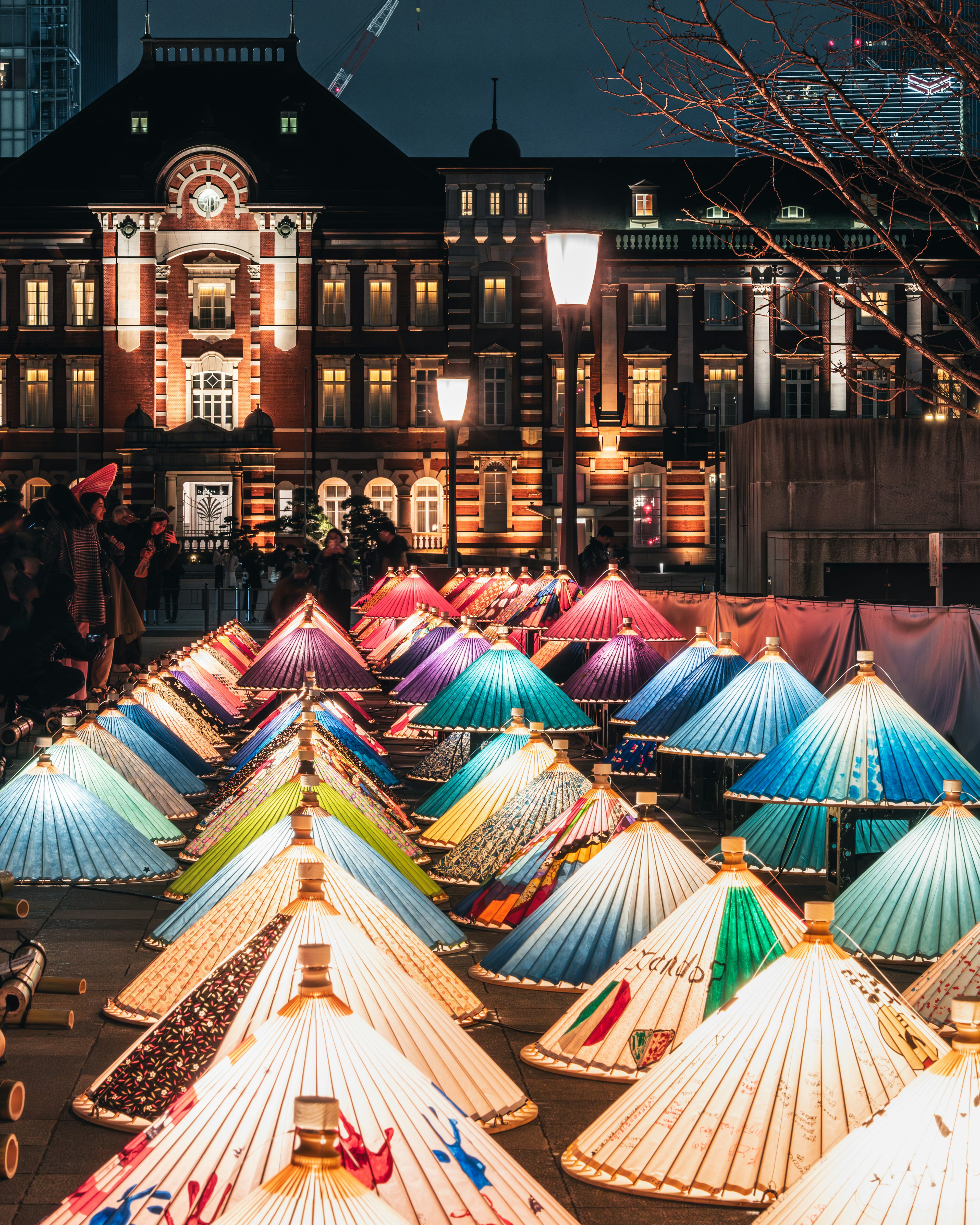 Colorful traditional umbrellas arranged in front of Tokyo Station at night