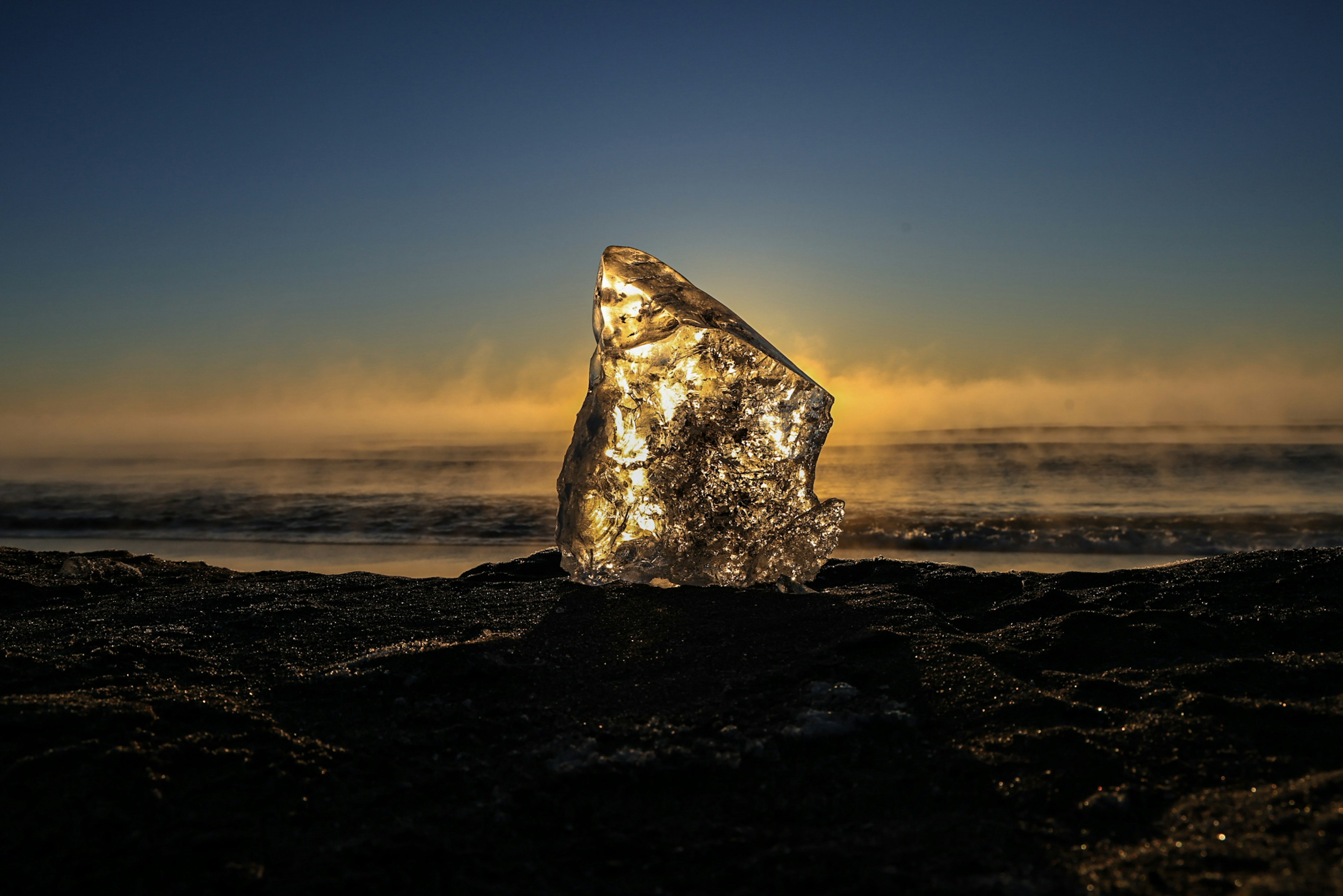 Glänzender Felsen am Ufer mit Sonnenuntergang im Hintergrund