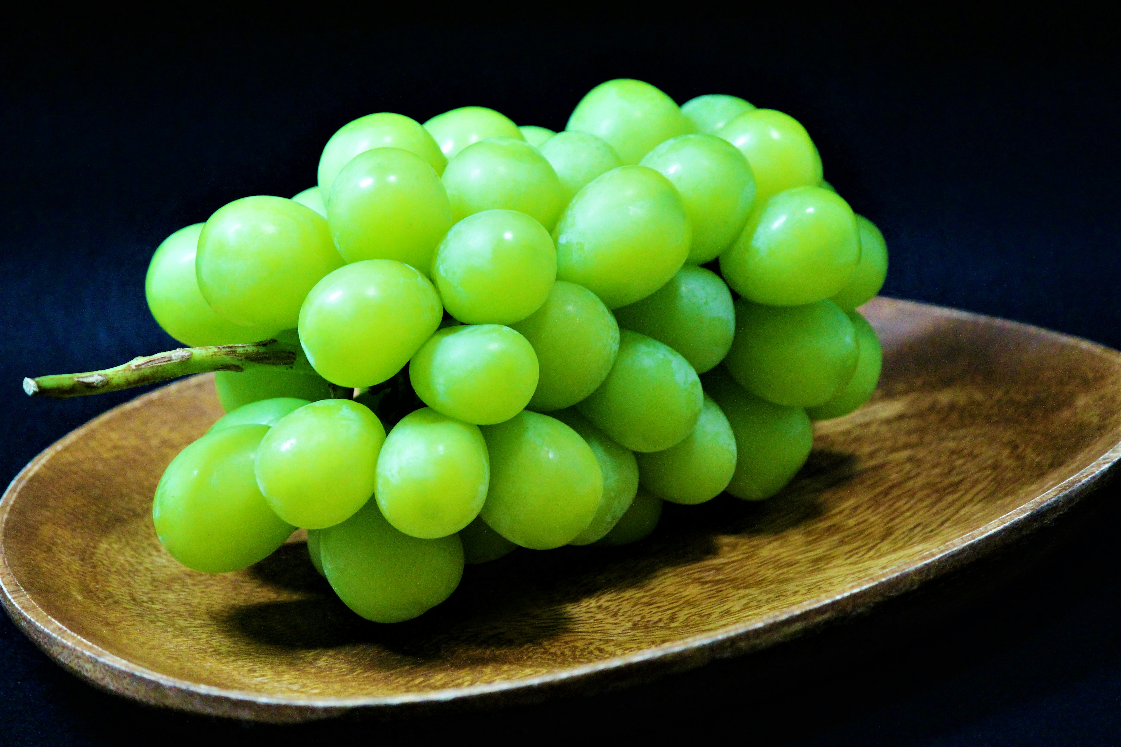 Un racimo de uvas verdes en un plato de madera