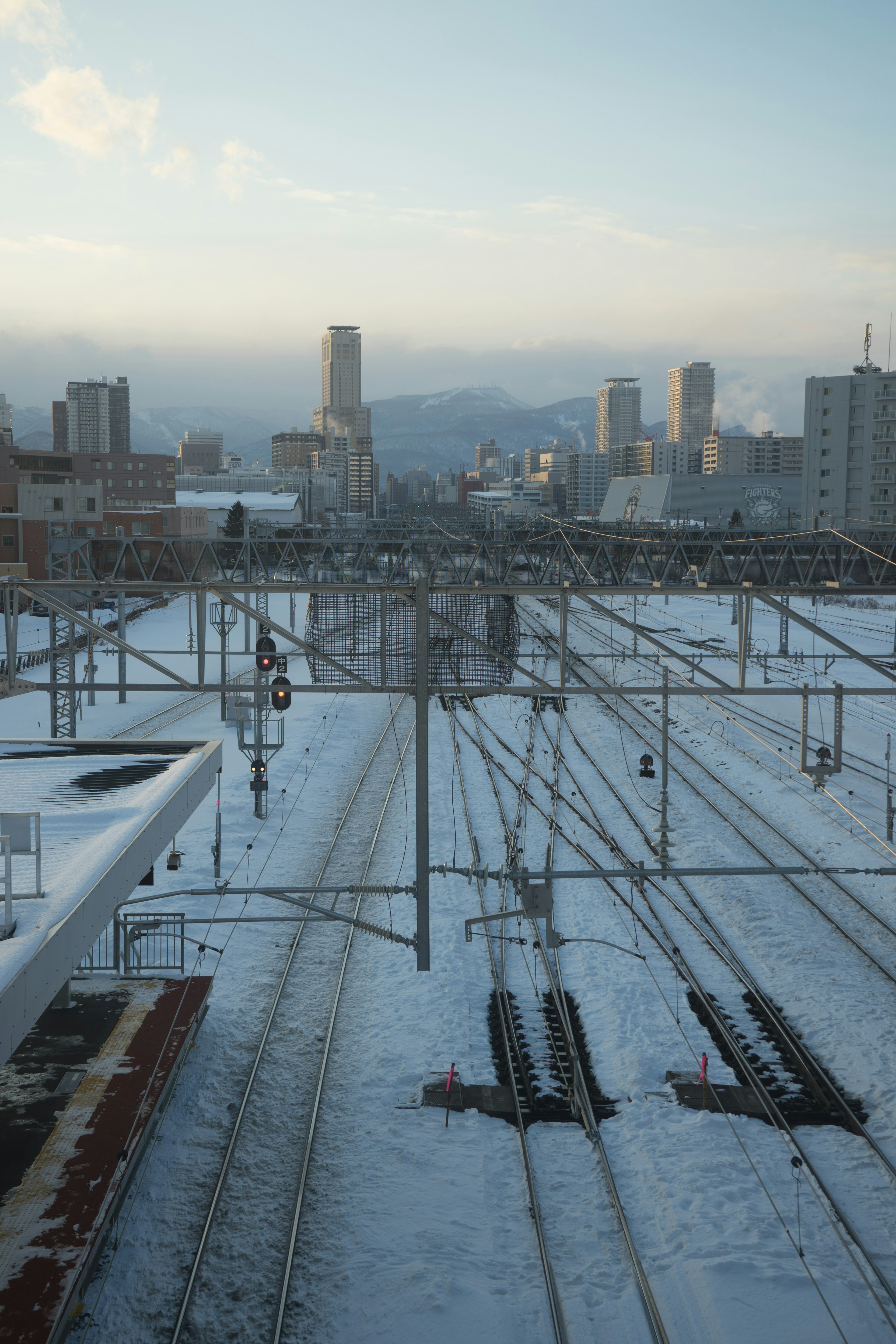 Snow-covered railway tracks with a city skyline