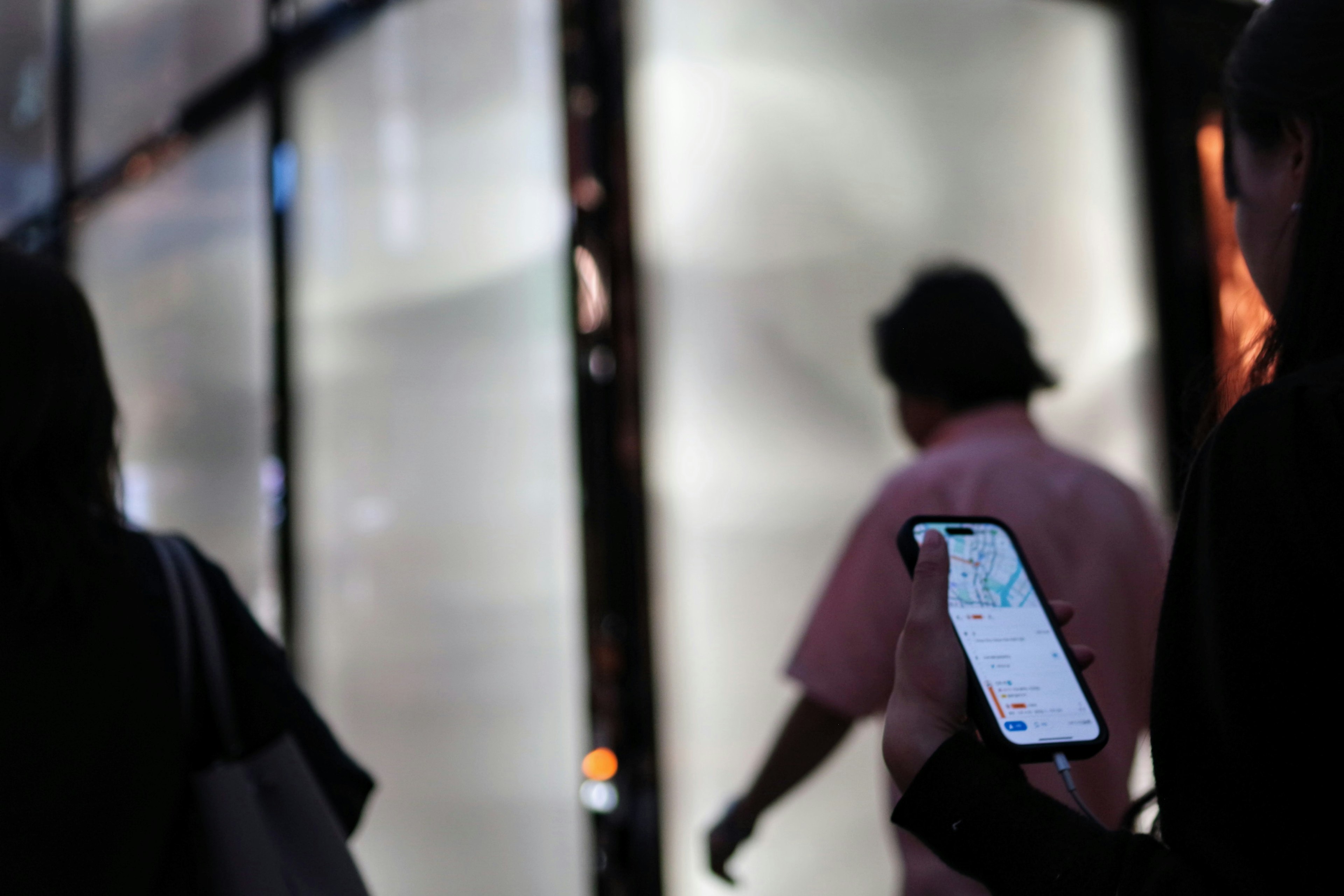 Mujer sosteniendo un smartphone con personas caminando en un fondo urbano