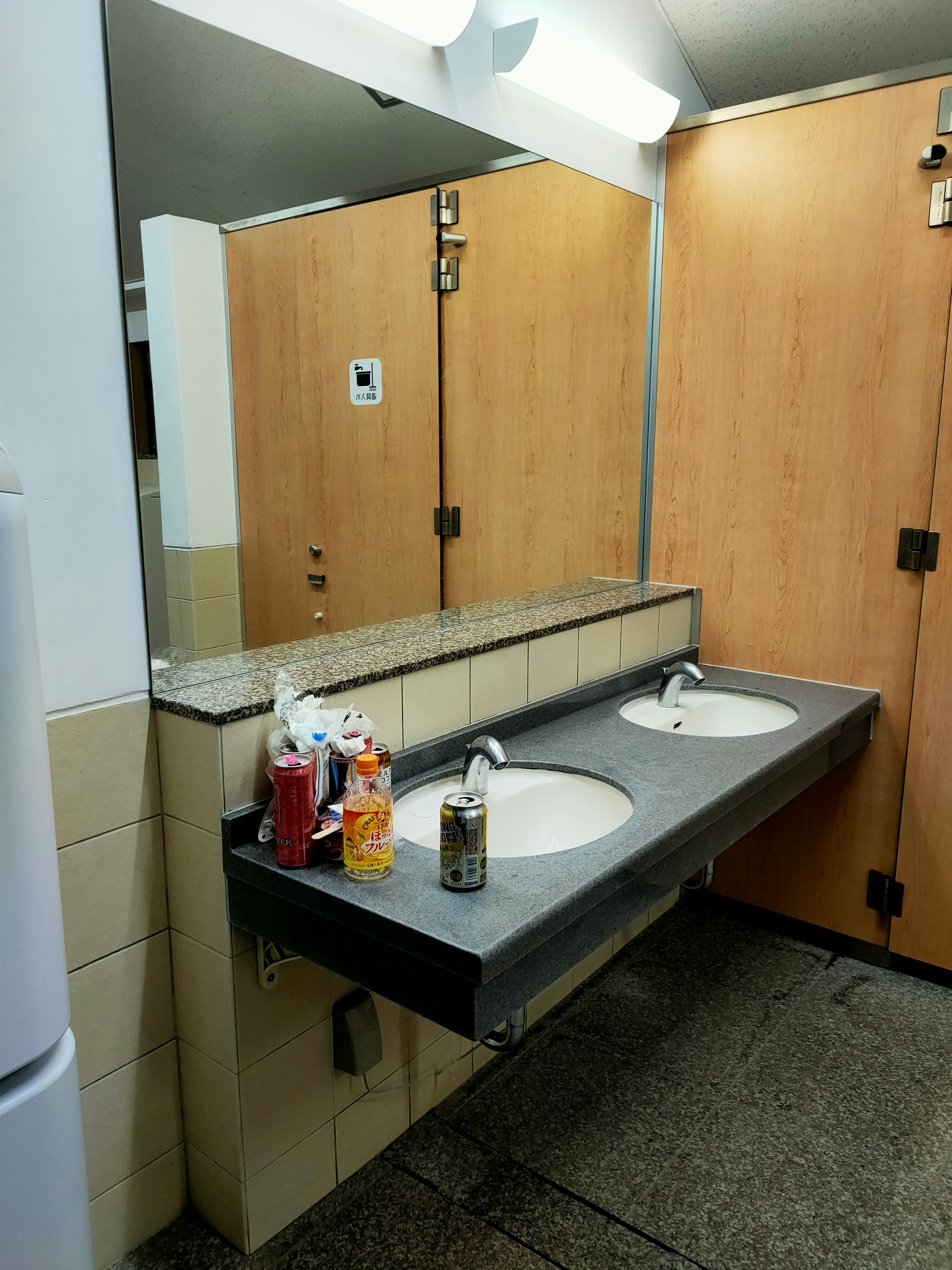 Interior of a public restroom with two sinks wooden doors and lighting