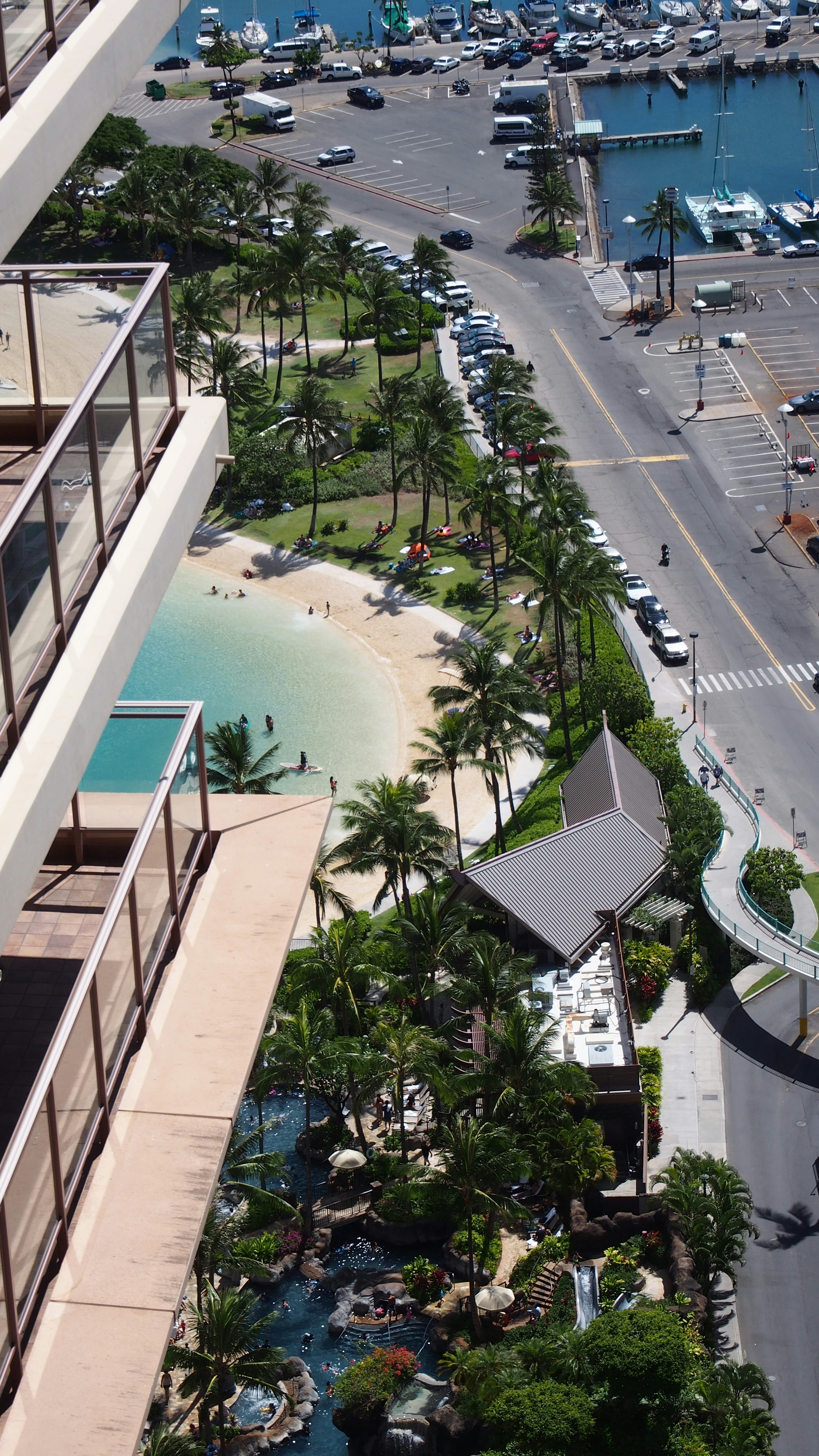 Luftaufnahme eines Strandes und einer Marina von einem Hochhaus mit üppigem Grün und einem Pool