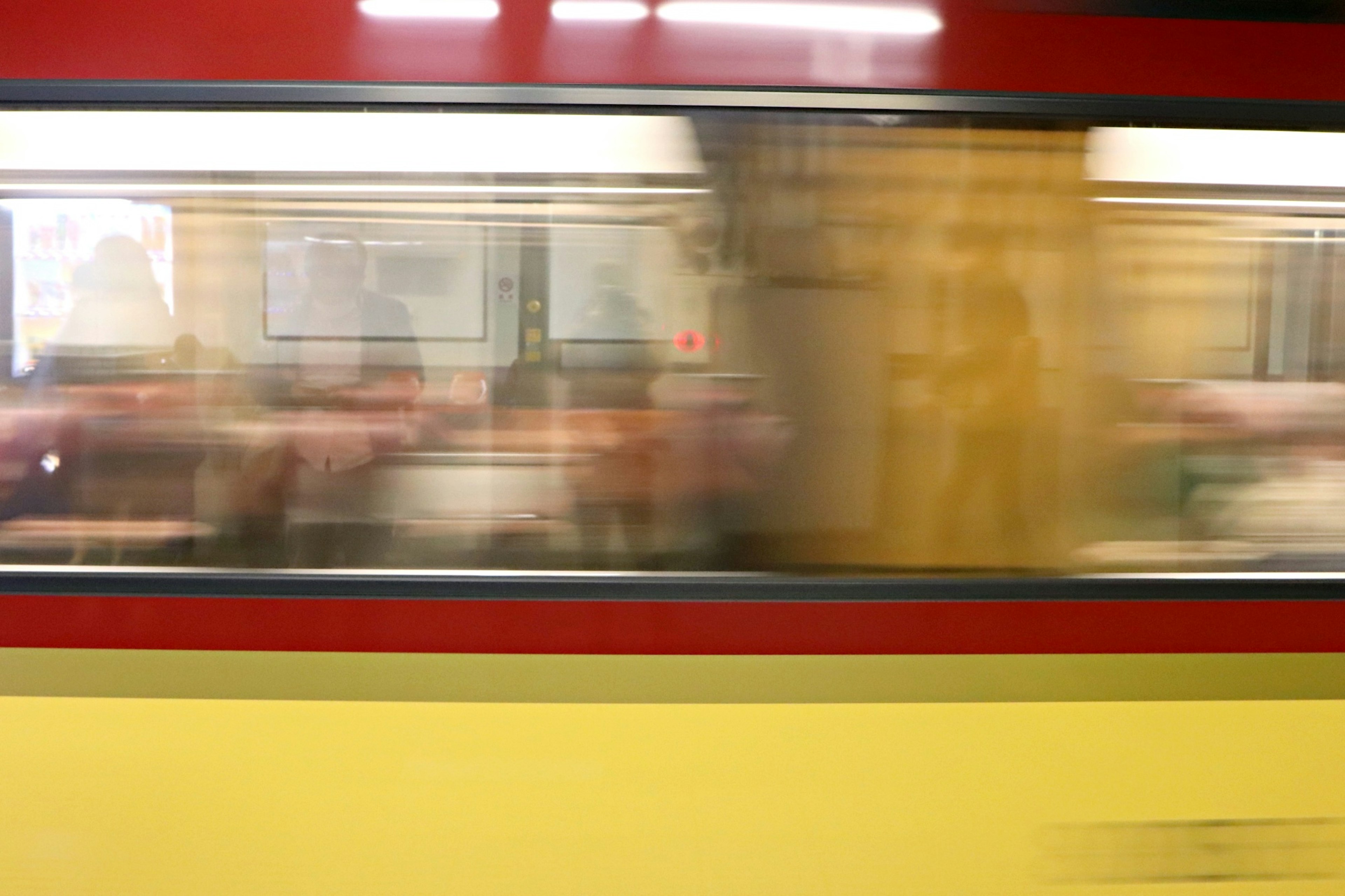 Vista borrosa de pasajeros dentro de un tren en movimiento a través de la ventana