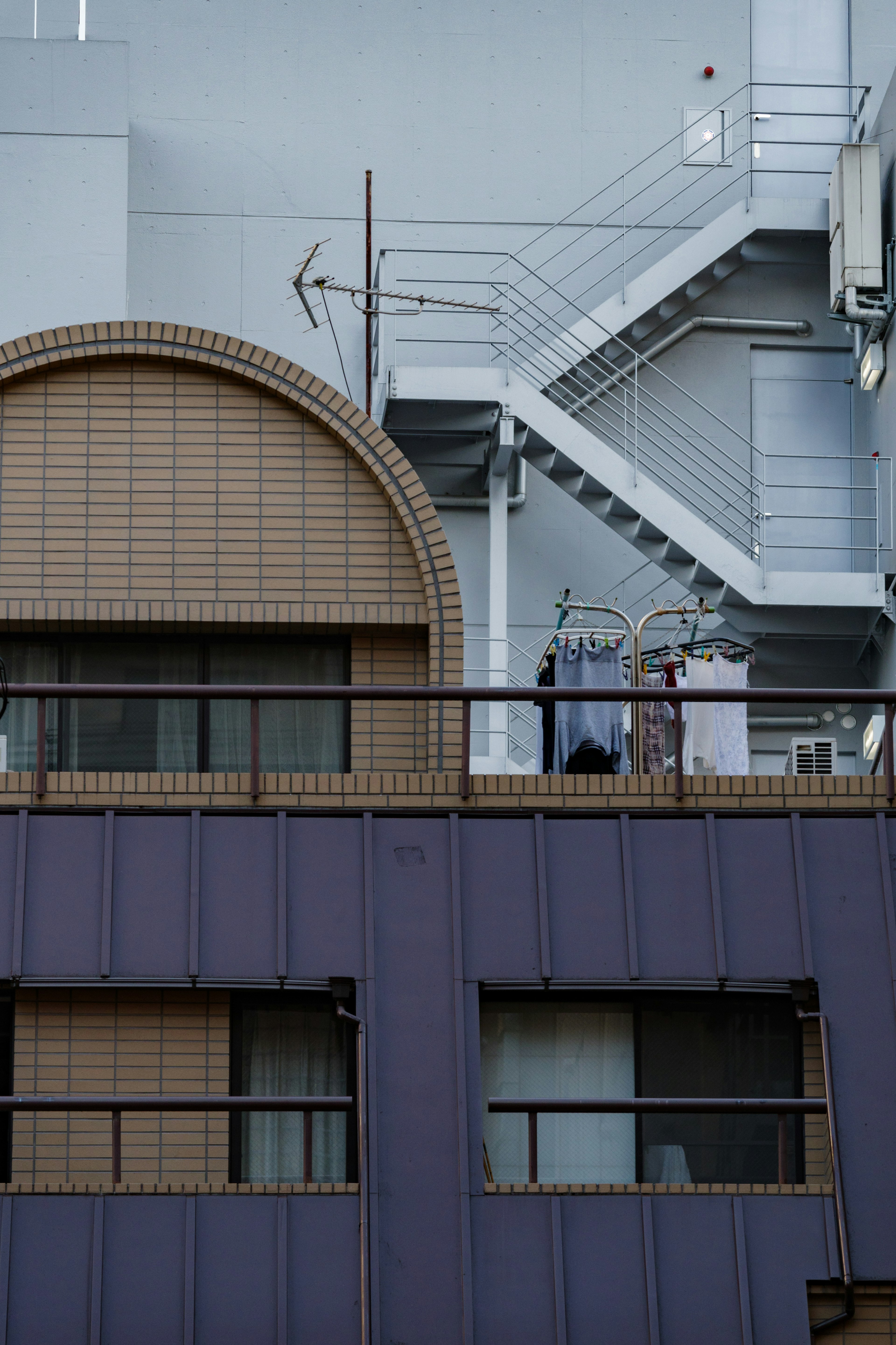 Parte de un edificio con un balcón con ropa y una escalera exterior