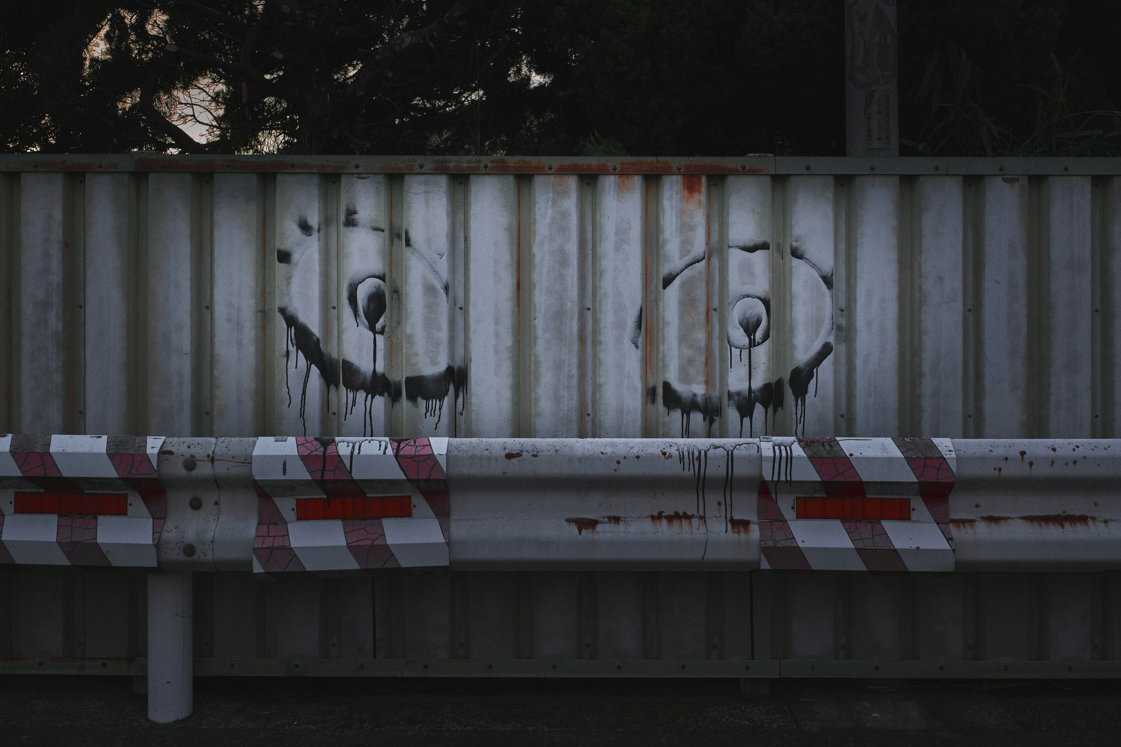 Grafiti que se asemeja a ojos en una barrera metálica con franjas rojas y blancas