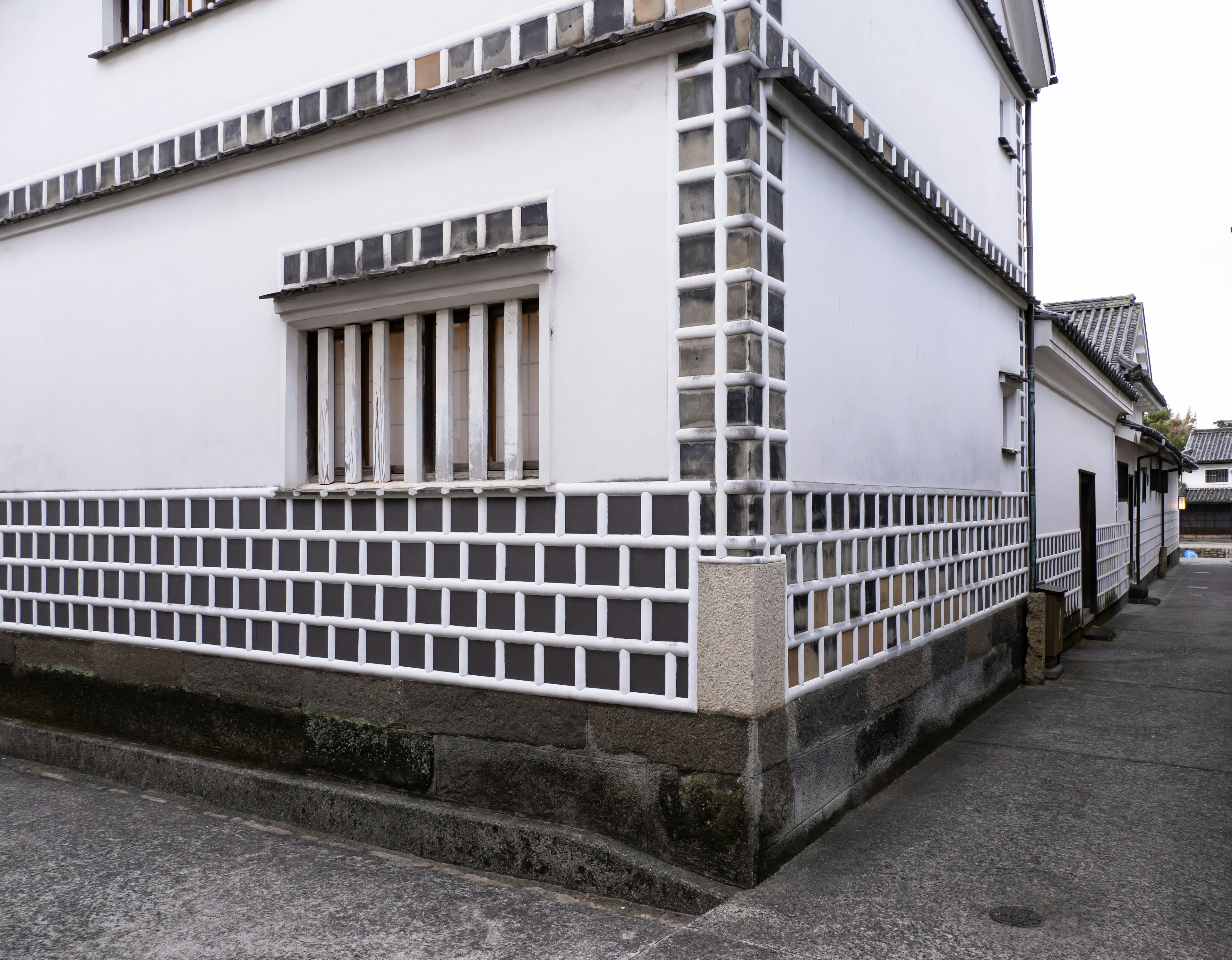 Esquina de un edificio con paredes blancas y patrones de azulejos grises