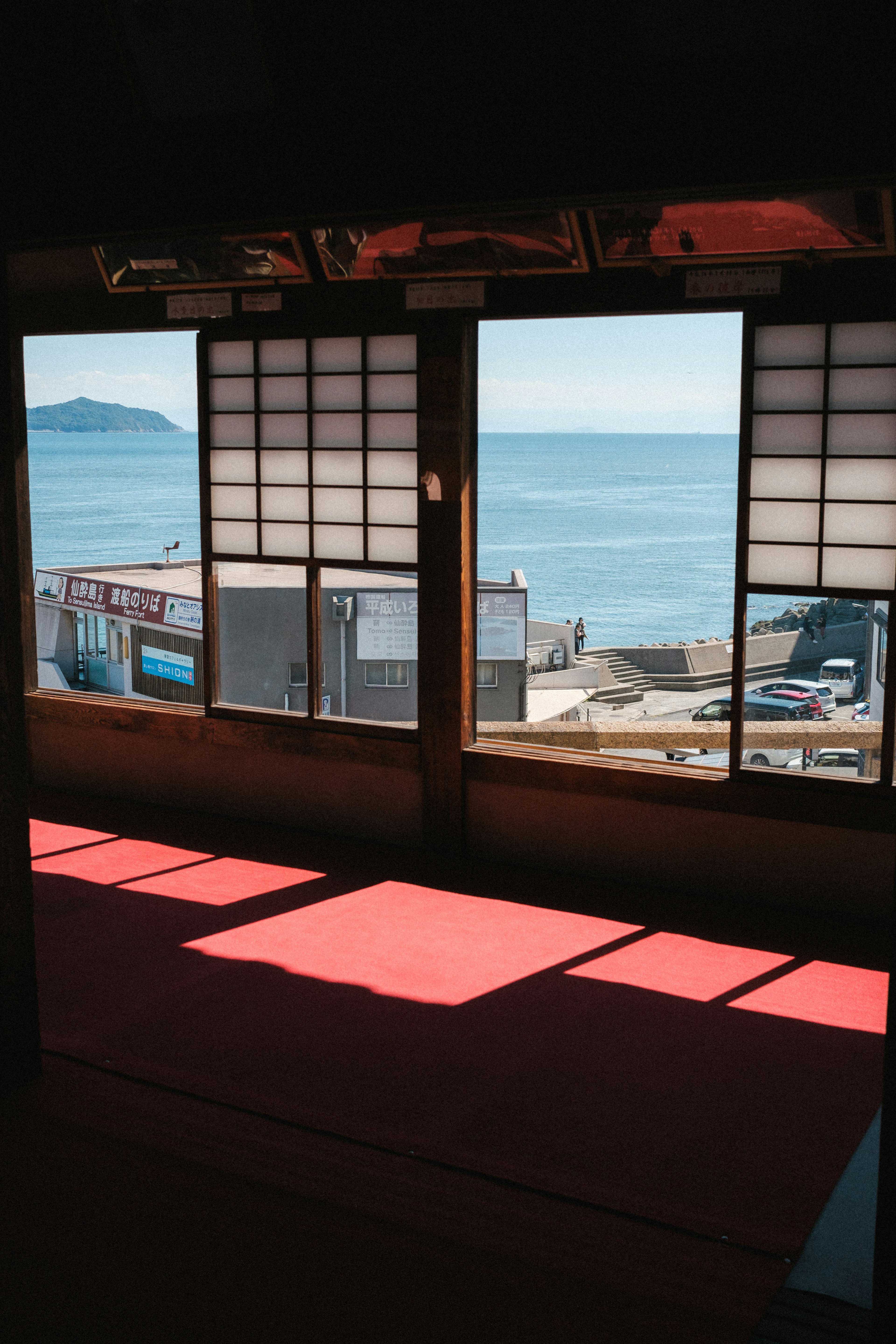 View from a traditional room with wooden windows overlooking the sea and red tatami mats