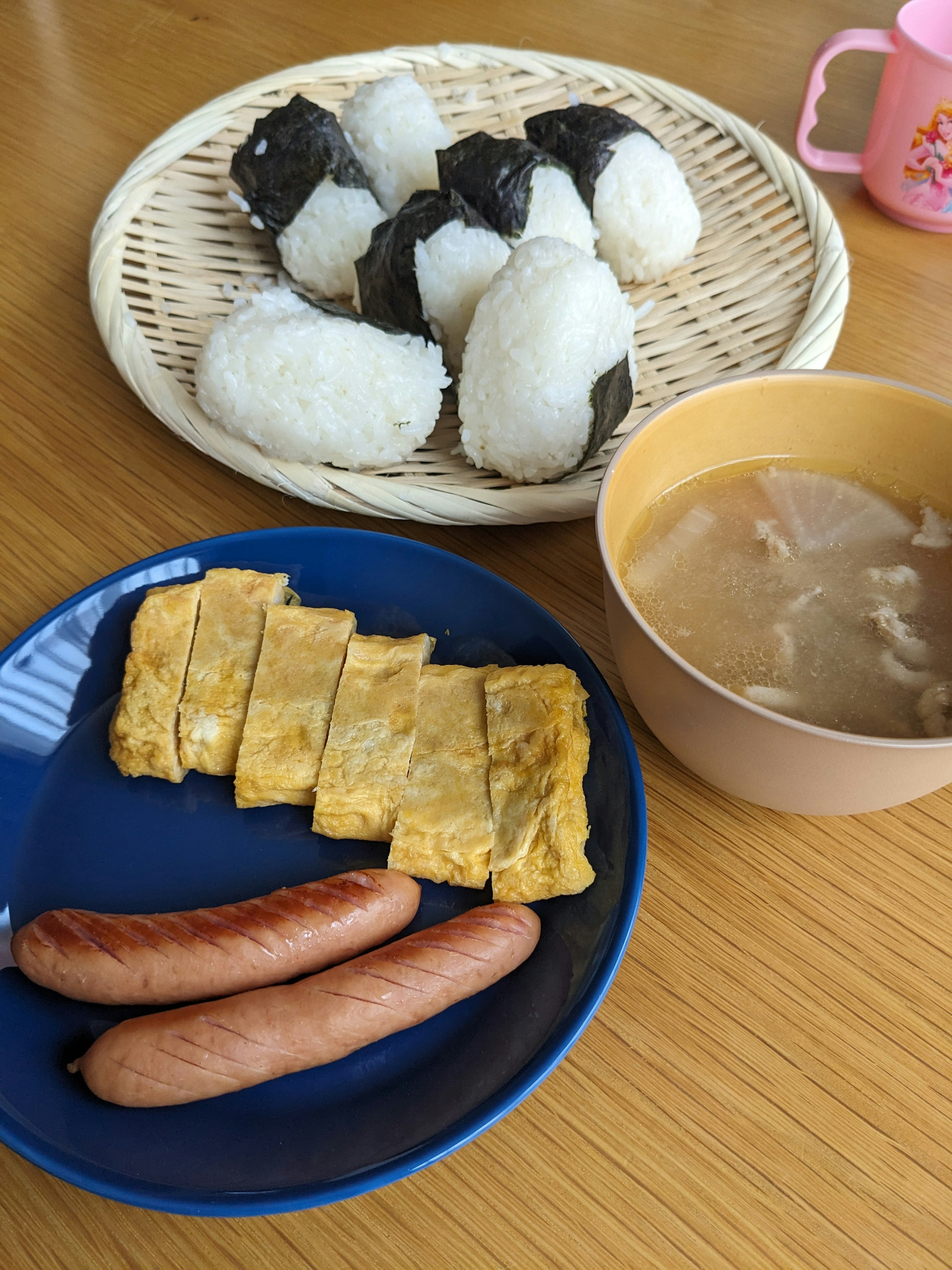 Un plato de desayuno con onigiri, tamagoyaki, salchichas y sopa de miso